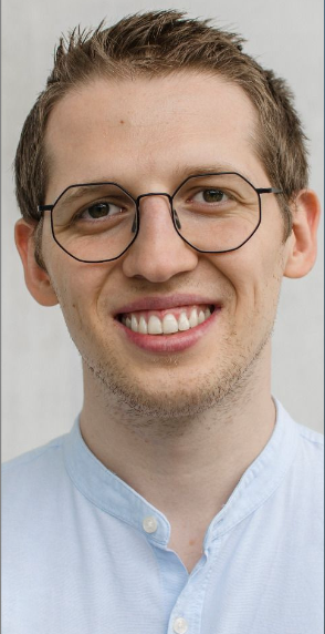 A man with glasses smiling at the camera.