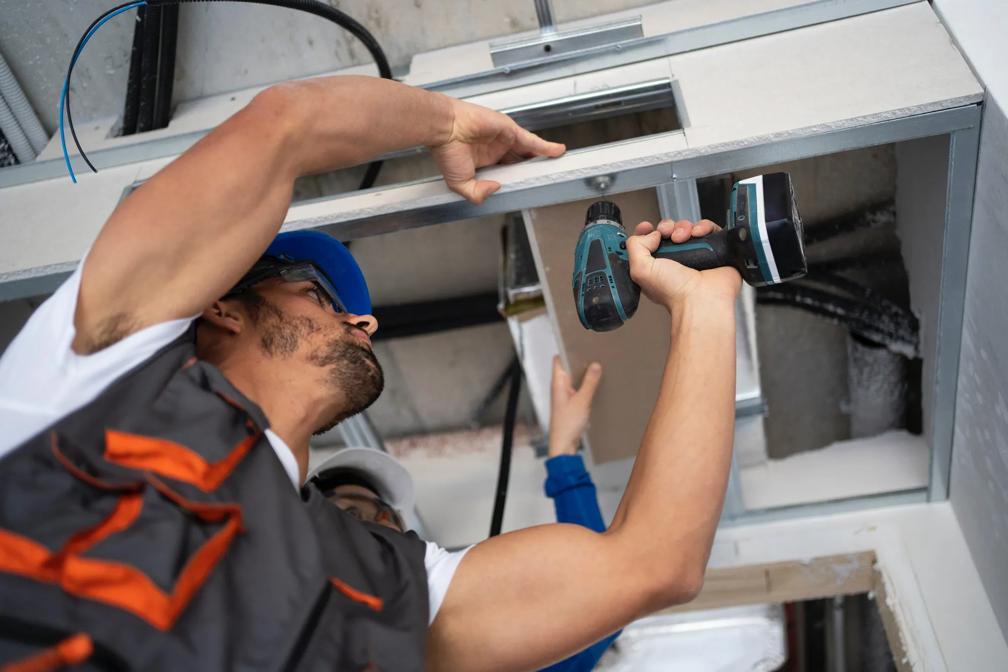 Technician installing equipment using power drill in electrical cabinet