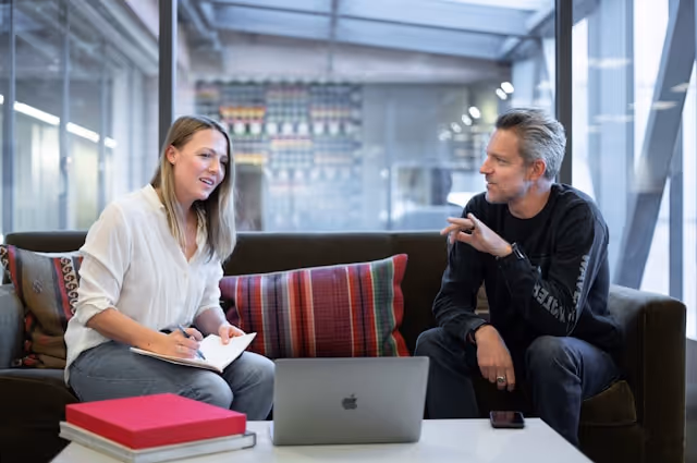 man and woman sitting on a sofa with laptop on table