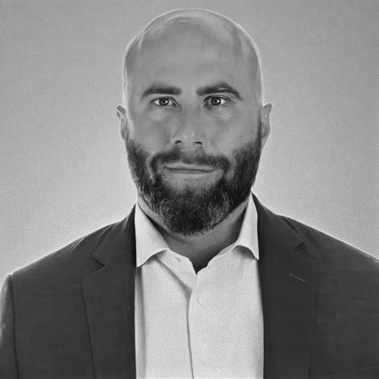 Black-and-white portrait of a man with a beard in a suit jacket.