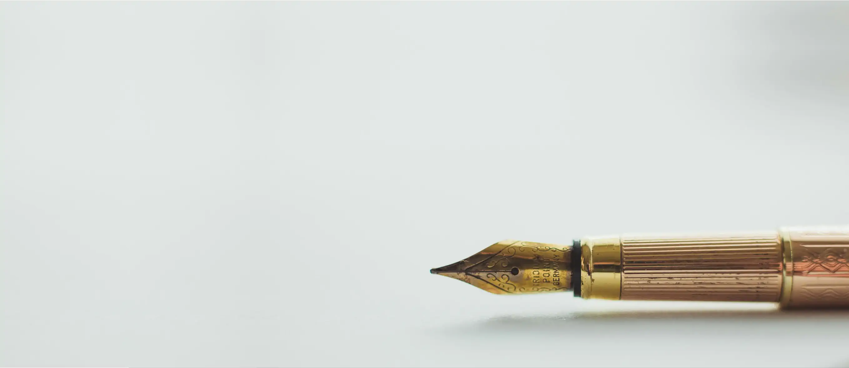 Photo of a golden fountain pen sitting on top of a white table.
