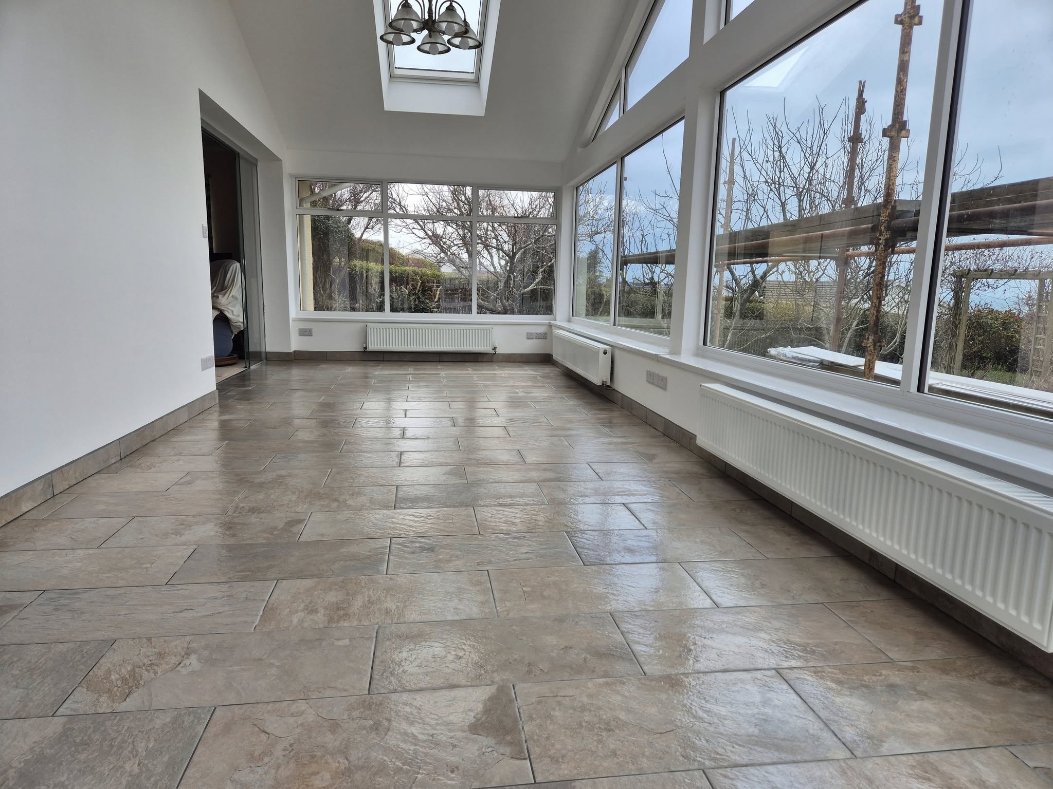 Modern sunroom with tiled floor and floor-to-ceiling windows.