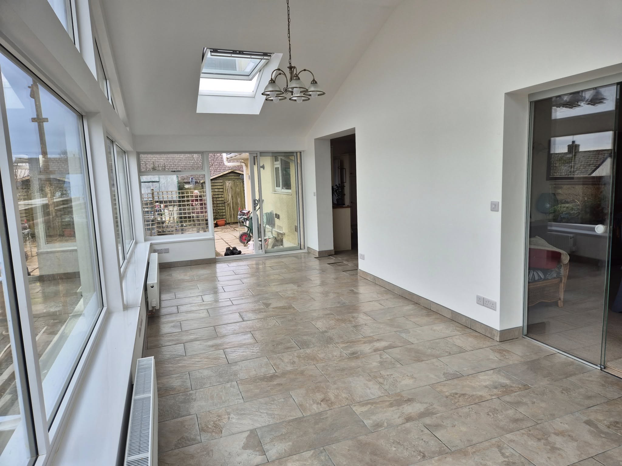 Bright sunroom with tiled floor and skylights, view to garden.
