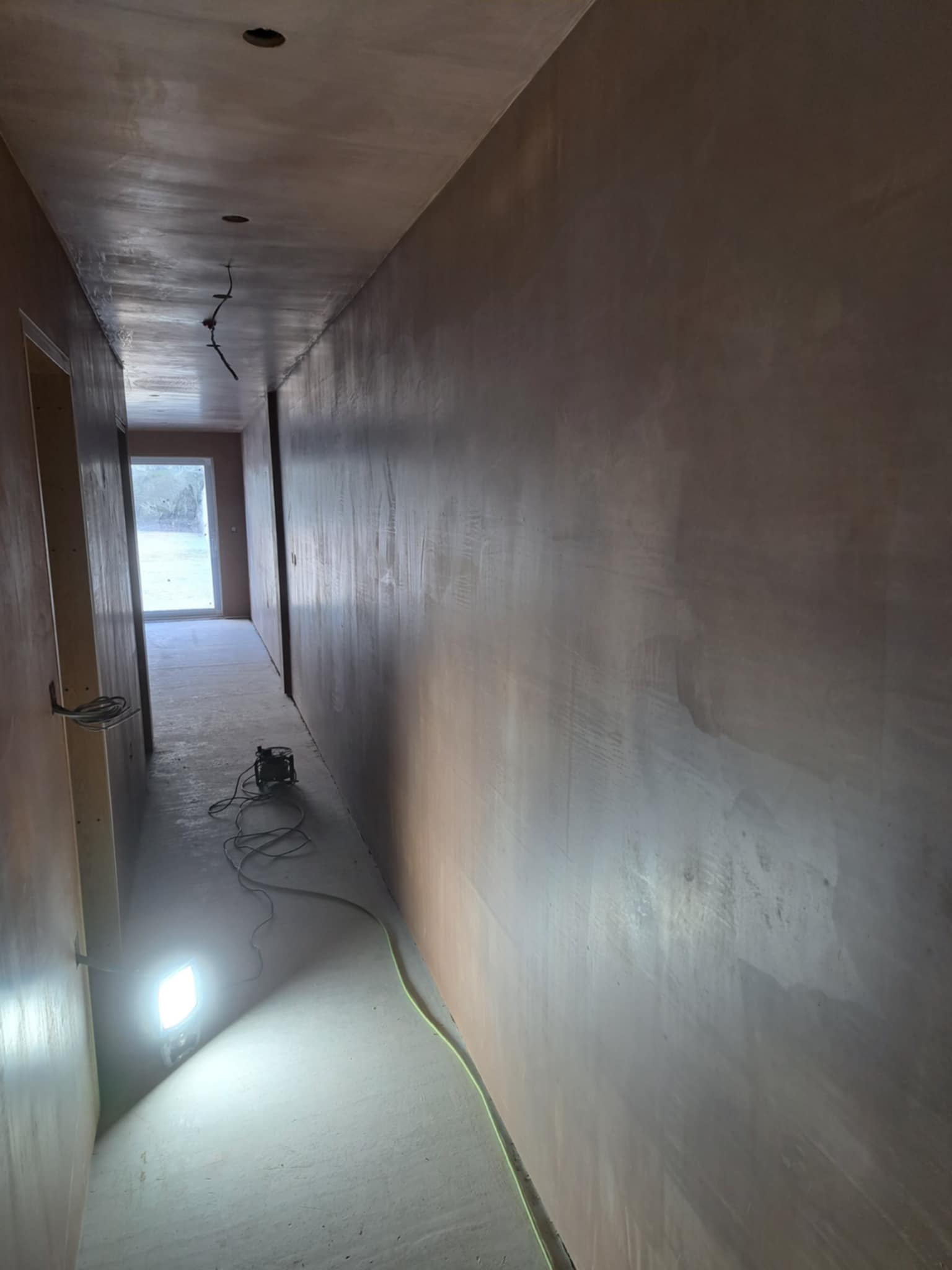 Long, narrow hallway with smooth new plaster on walls and ceiling.