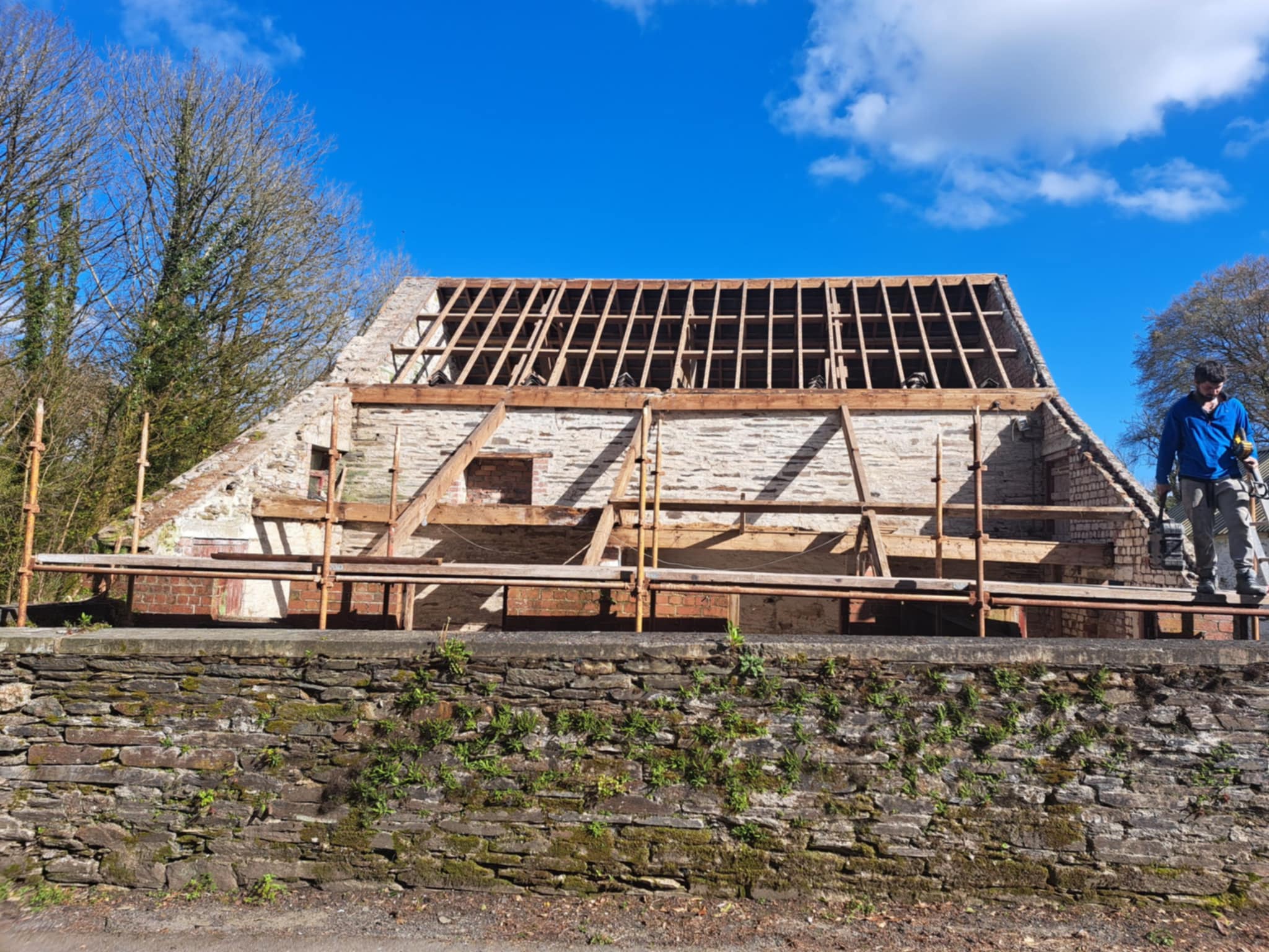 Timber roof structure under construction, viewed from behind a wall.