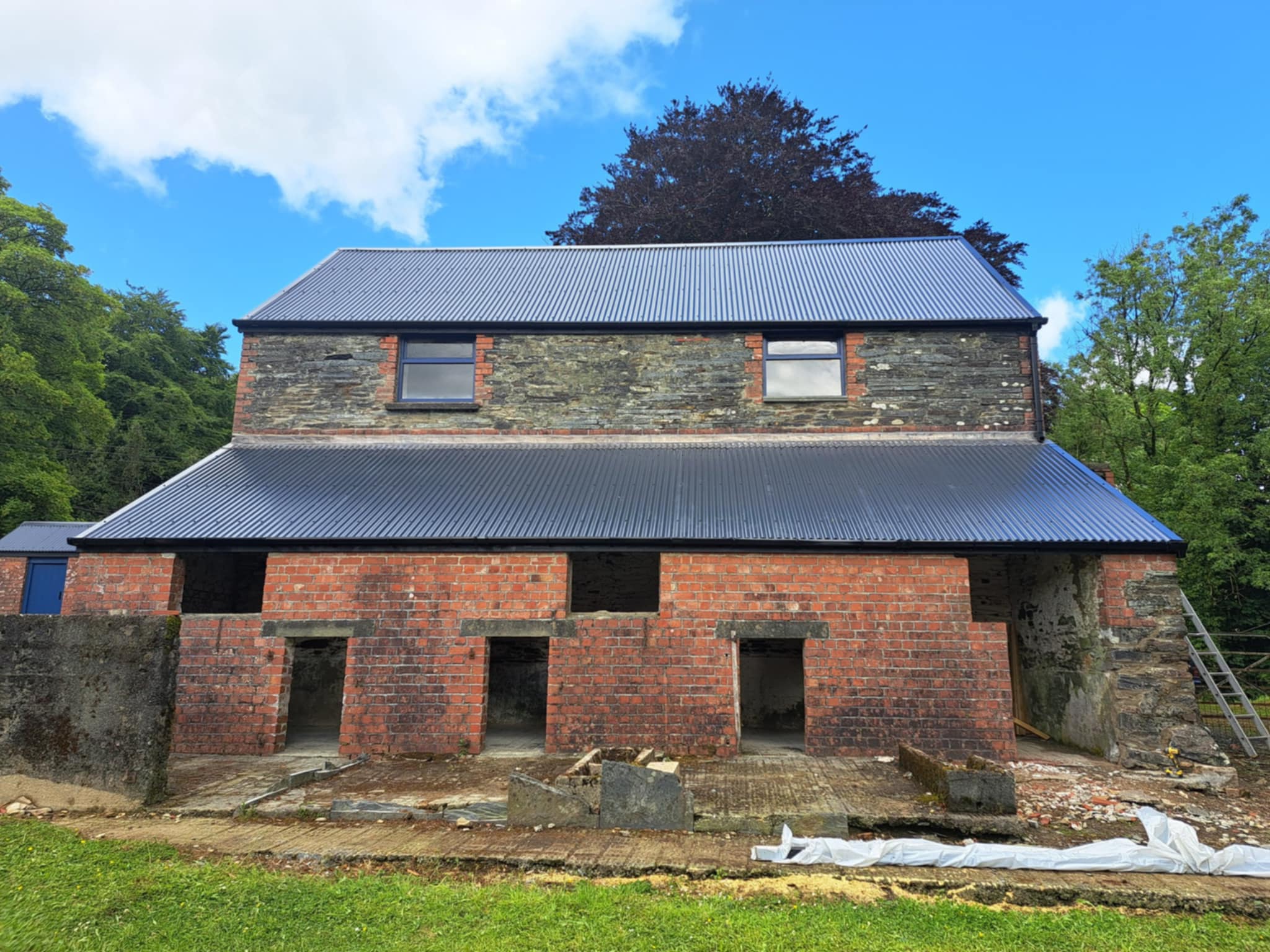 Brick barn with new roof, photographed from a distance.