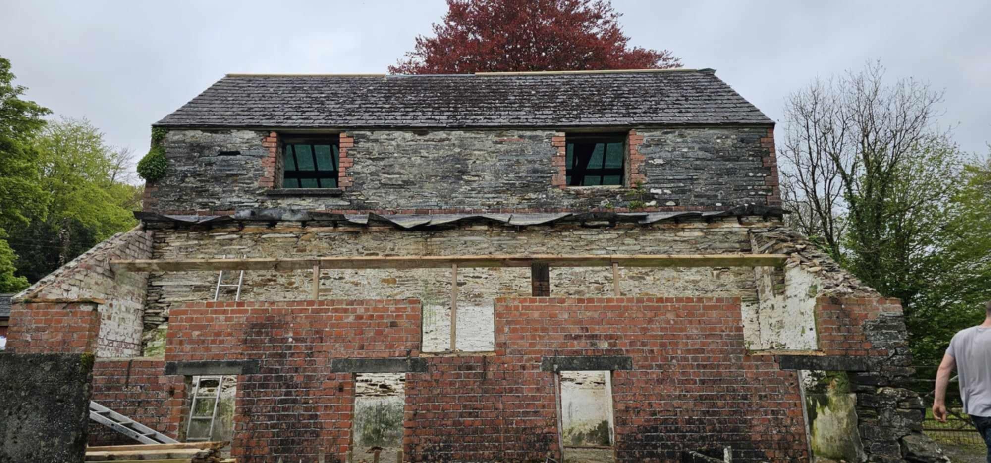 Brick barn with new roof structure, scaffolded, front view.