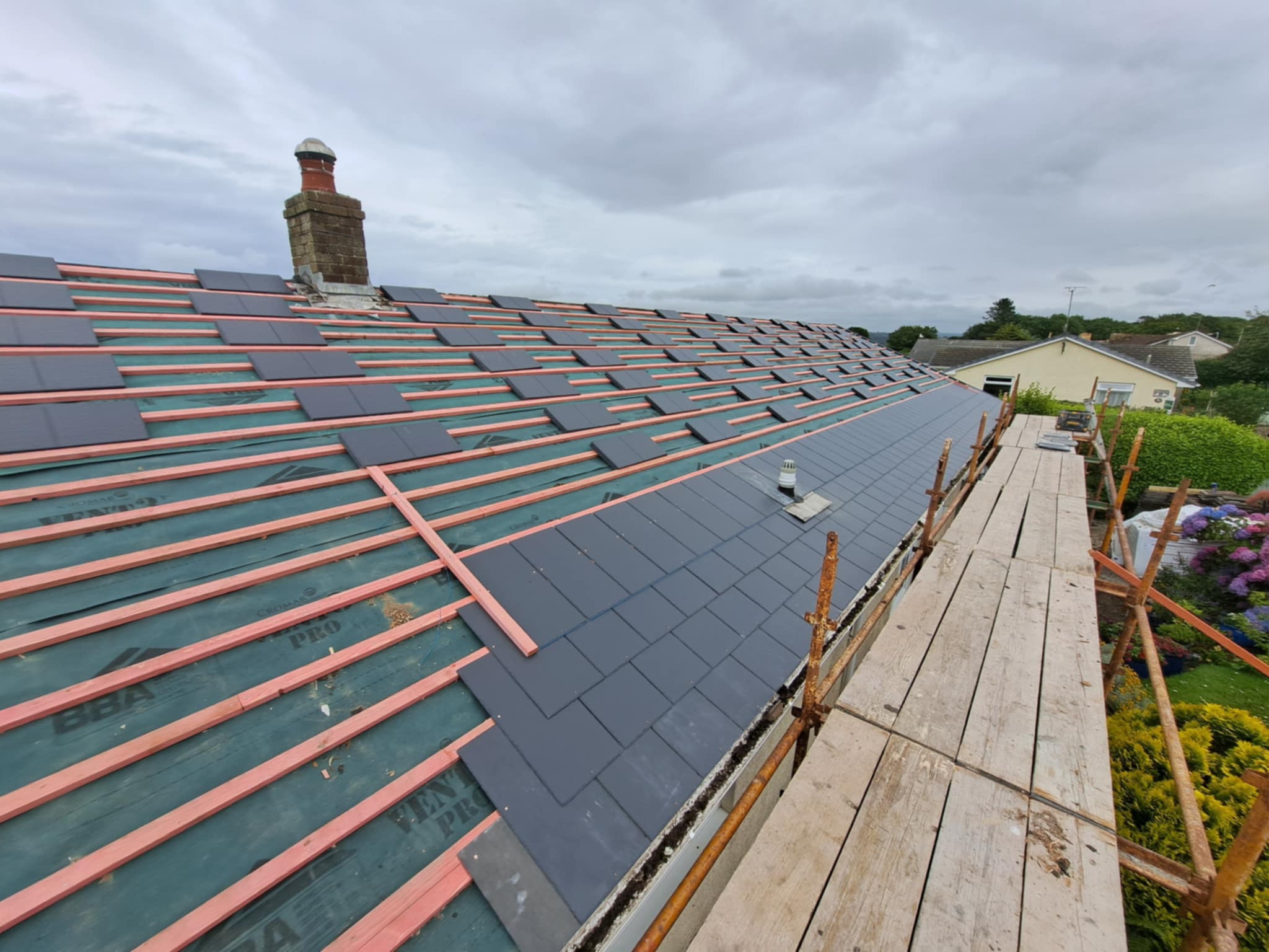 Pitched roof with battens viewed from the side, garden below.