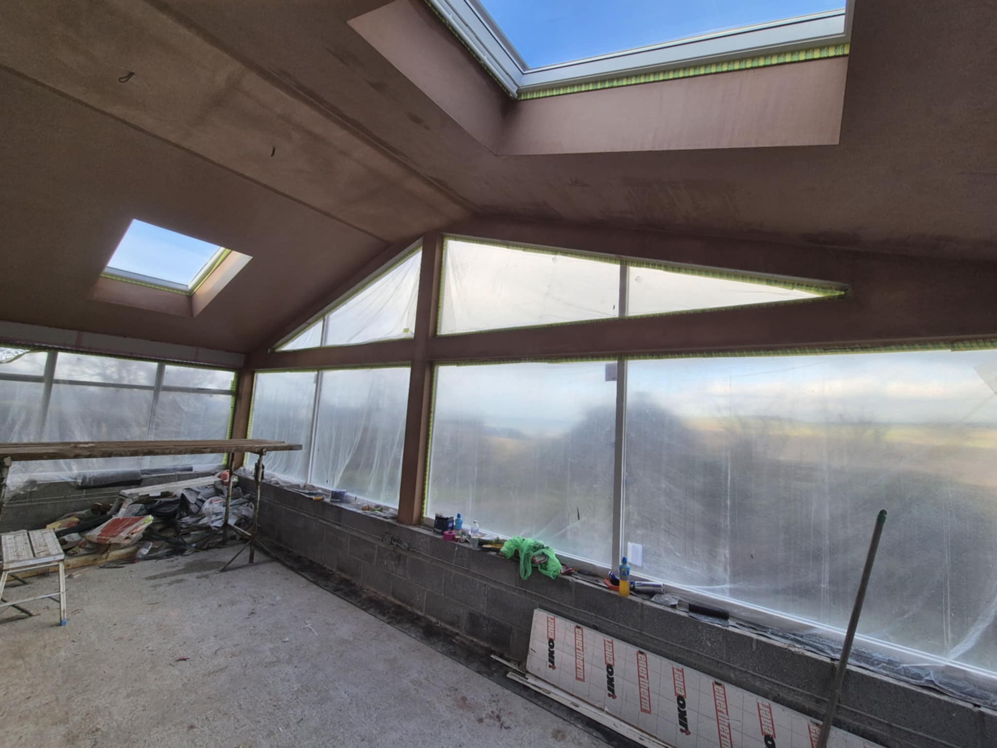Interior of a sunroom with skylights and large windows, partially finished.
