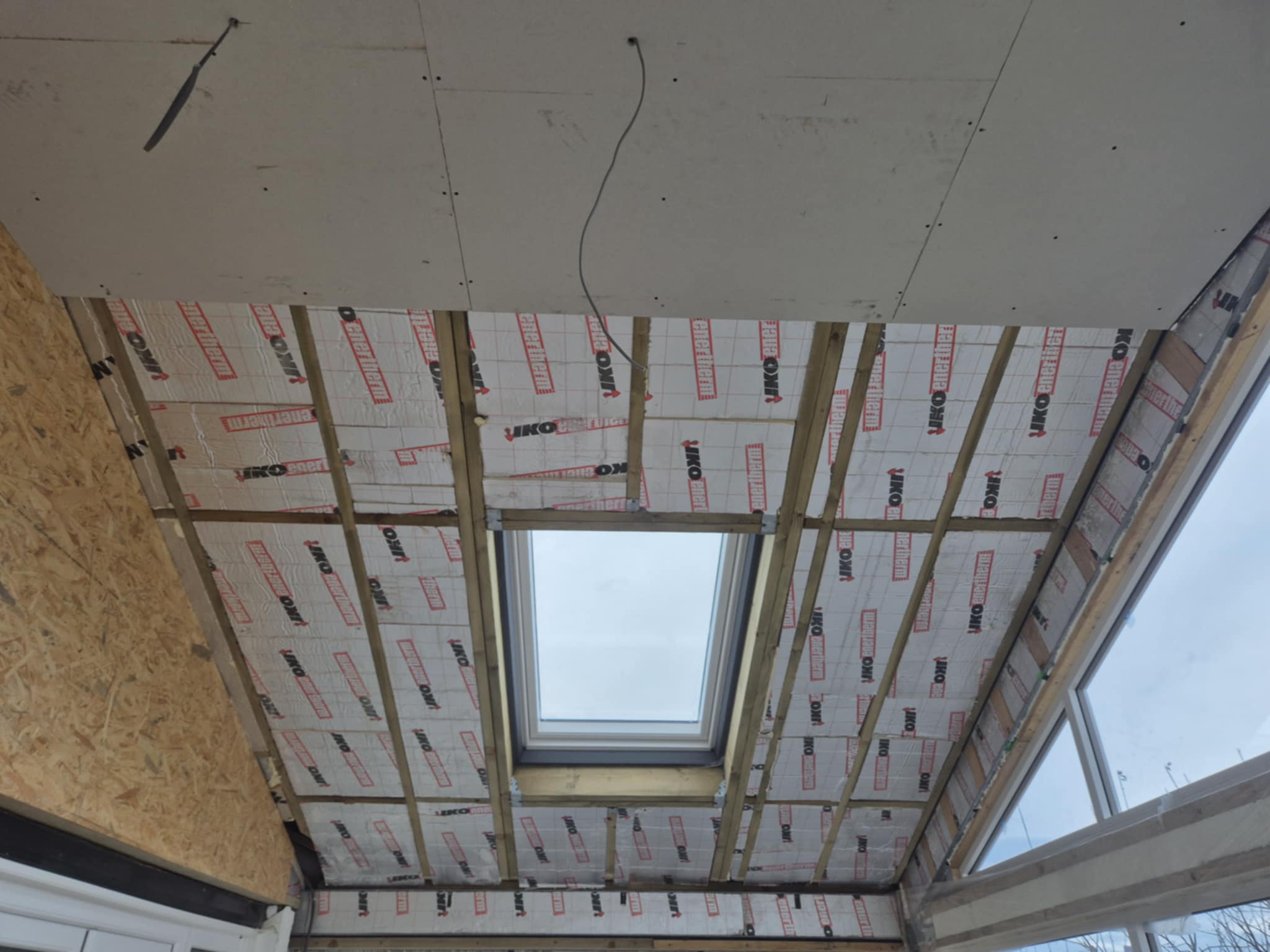 Interior ceiling view showing fitted insulation boards and exposed timber beams.