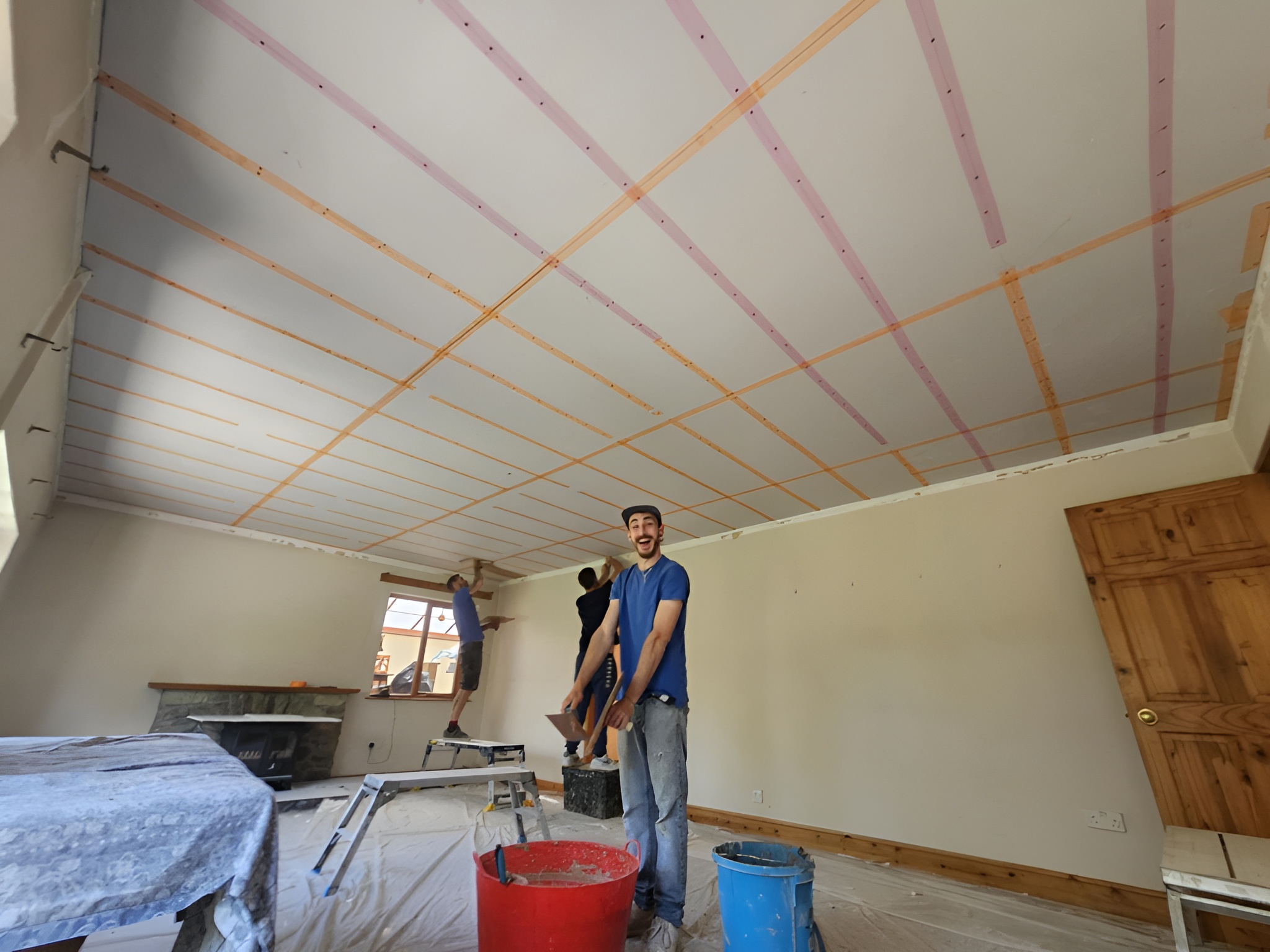 A person working in a room with ceiling insulation visible and building materials around.
