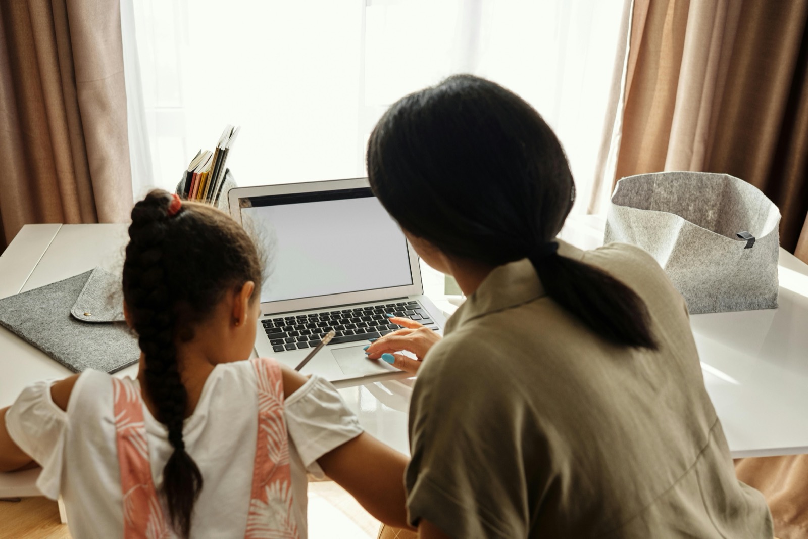 A guardian and student reviewing schoolwork together on a laptop