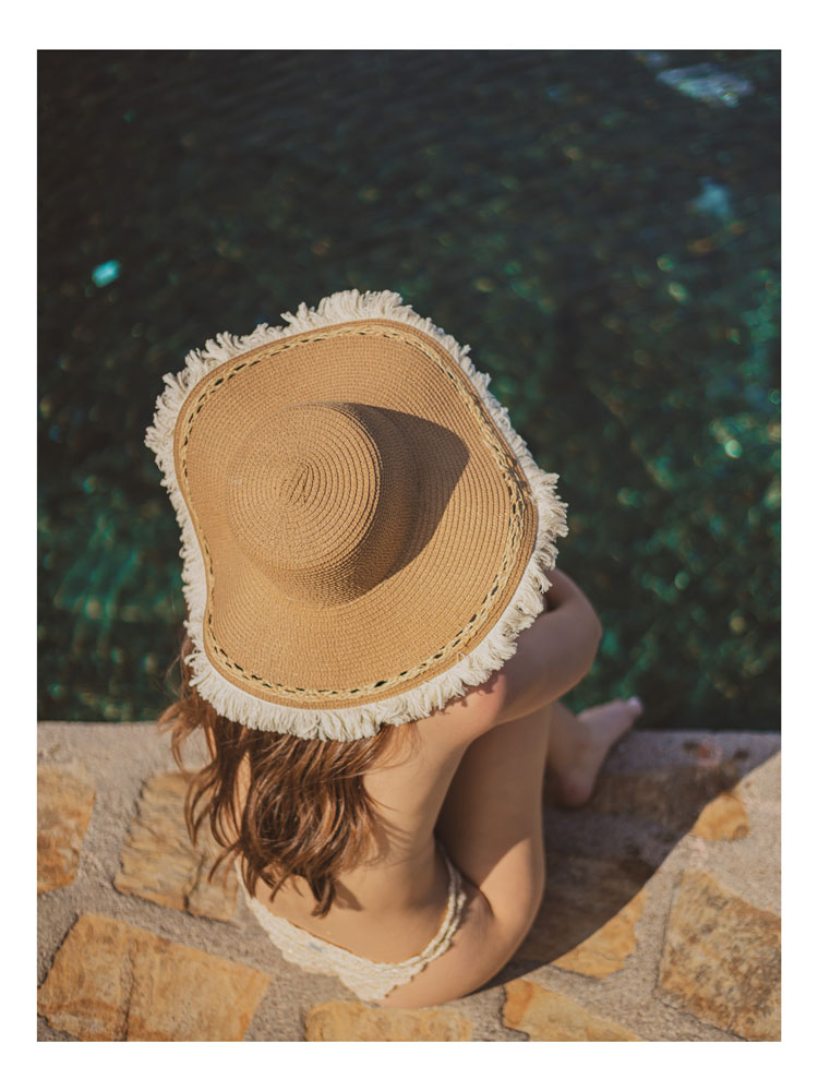 Photographie de Juliette Barcelo. Femme au chapeau au bord d'une piscine. 