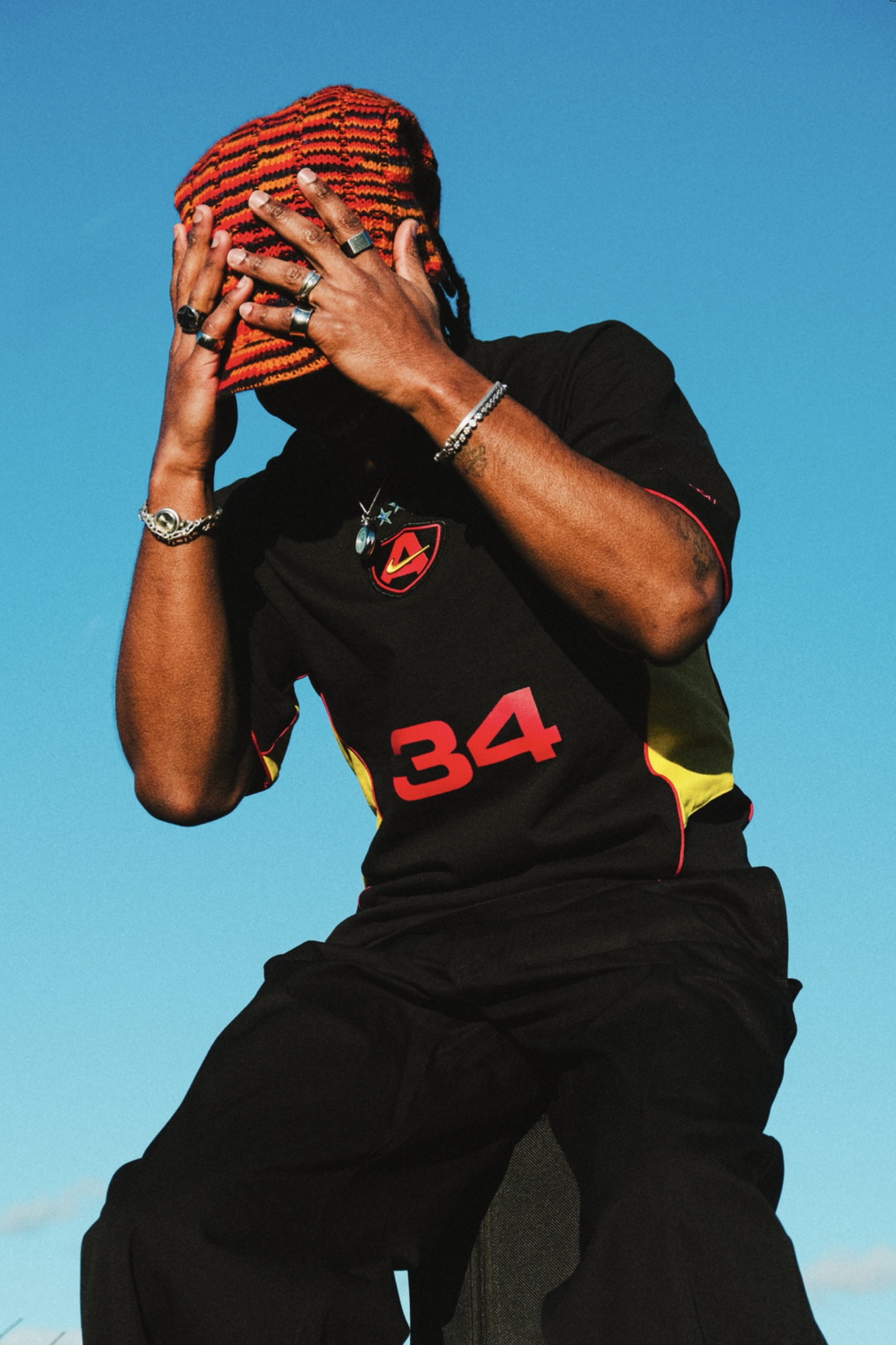 Photographie de Romane Kouo. Photographie d'un homme avec la tête entre les mains, avec seulement le ciel en fond. 