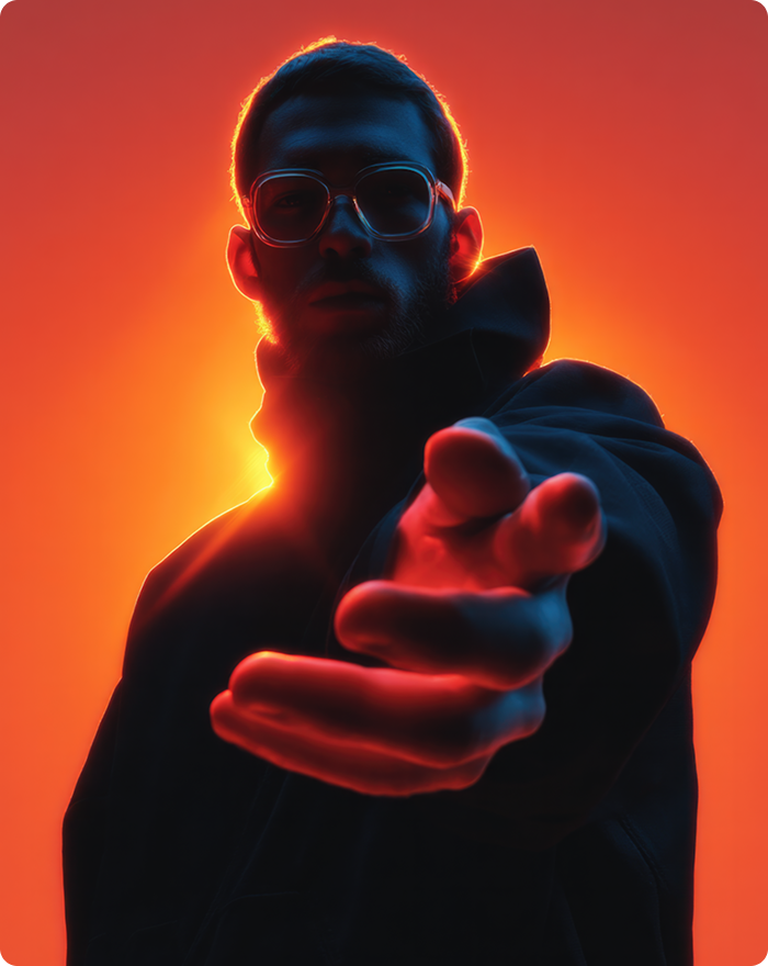 A man in sunglasses and a black jacket points at something off-camera, appearing engaged and focused.