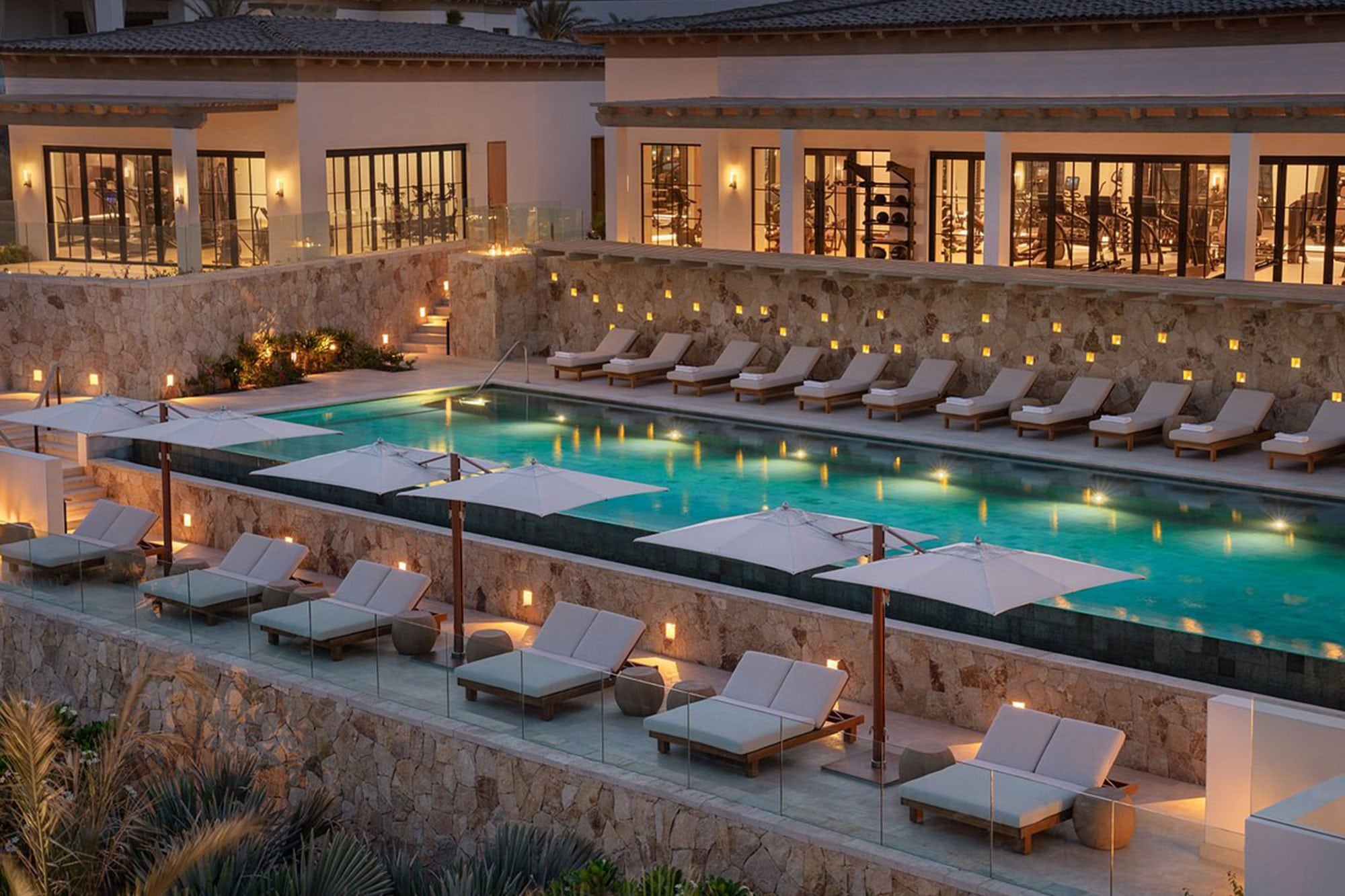 Luxury pool terrace with lounge chairs and umbrellas at Four Seasons Cabo del Sol, represented by Terentti