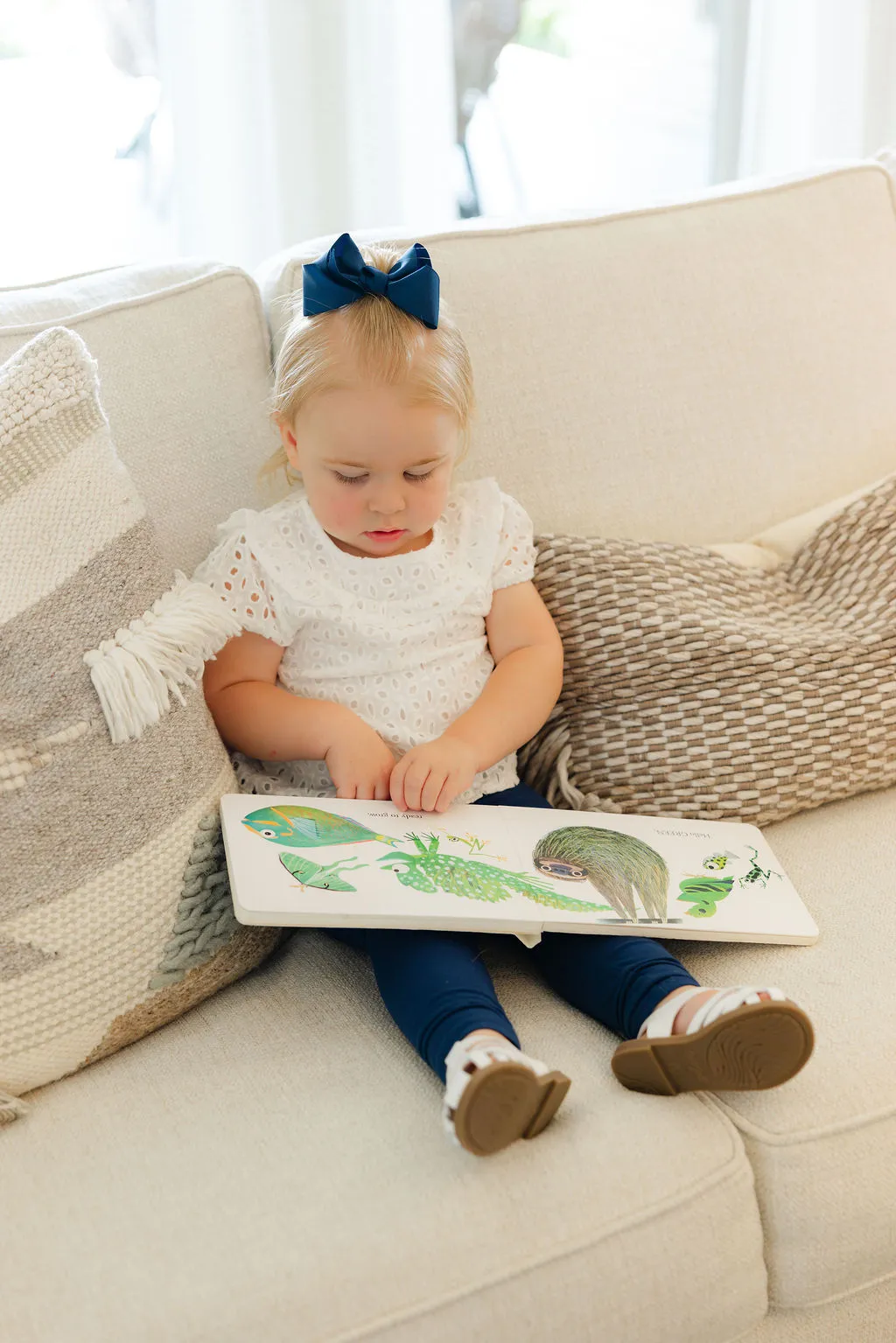 A baby on a couch looking at a coloring book.