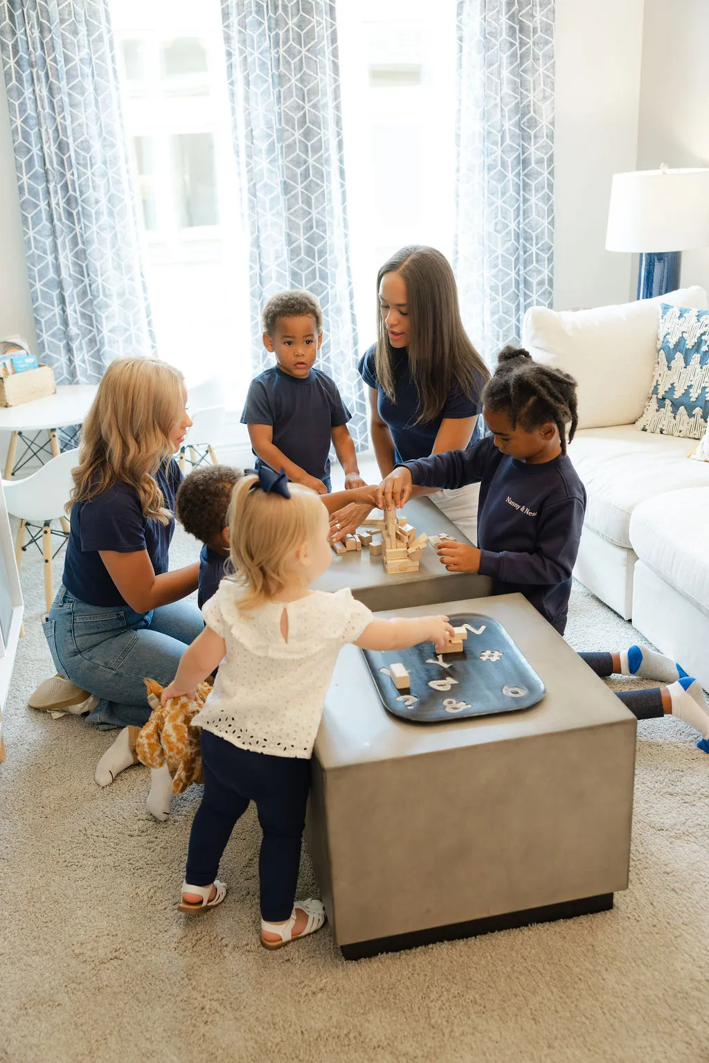 Children stacking blocks around a table in the living room.