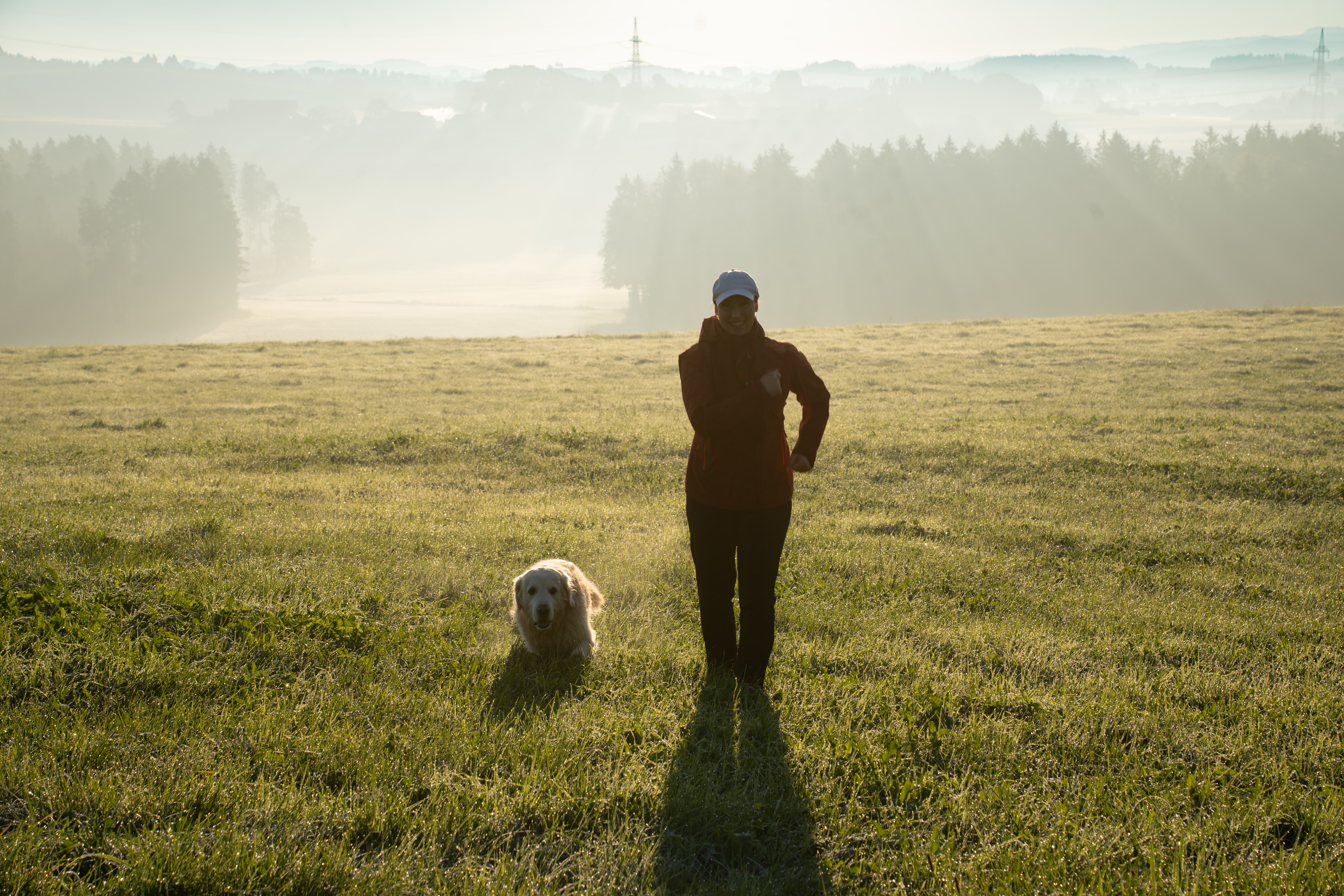 Doris und Jacky laufen bei Morgentau durch eine Wiese.