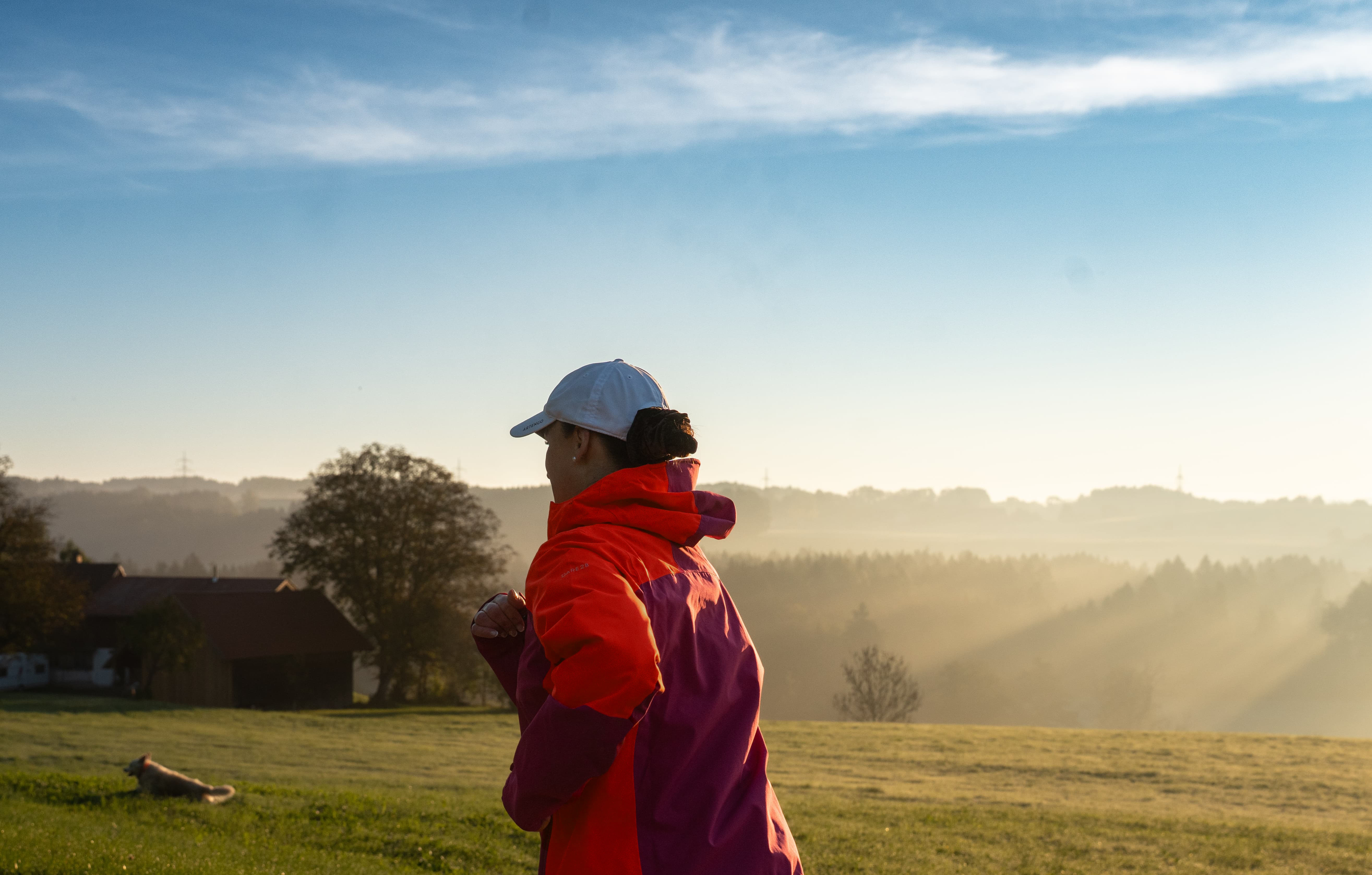 Doris von hinten beim Bajoli-Lauf mit Morgentau. Jacky springt voraus auf der Wiese.