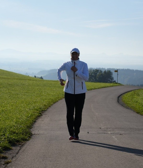 Doris läuft vor Bergkulisse und strahlt dabei glücklich.