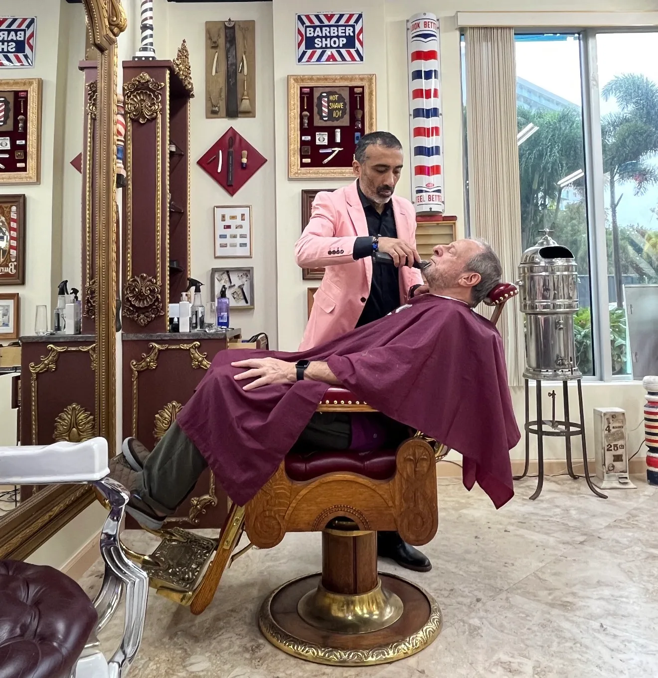 Sunlit vintage barbershop interior with three brown leather barber chairs, large round mirrors, exposed brick walls, and a patterned rug.