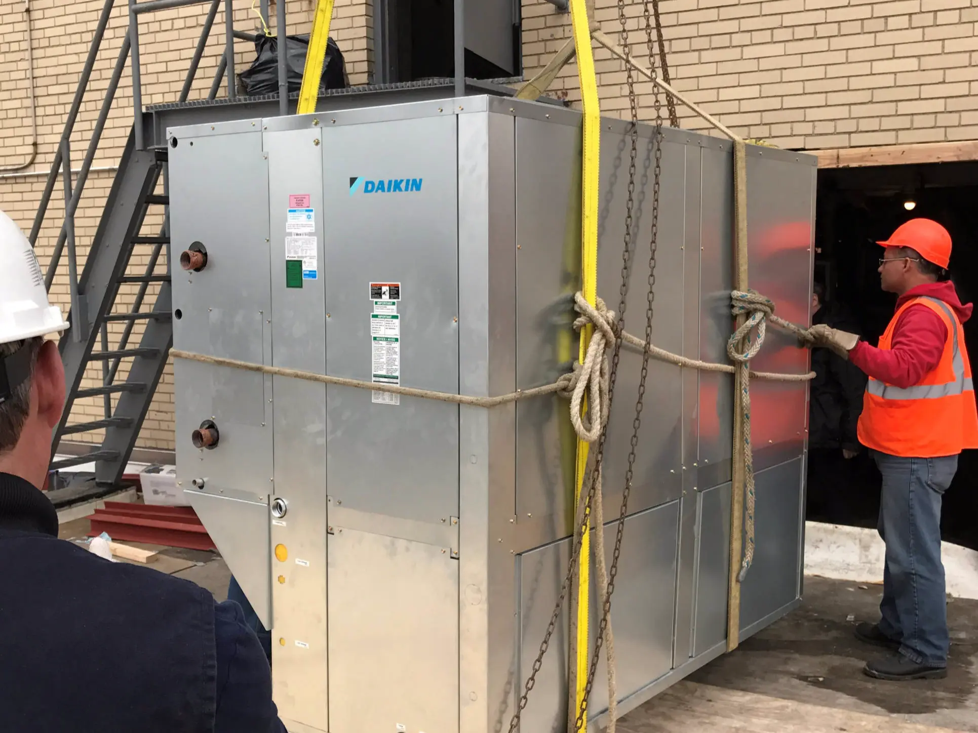 Daikin rooftop HVAC unit being guided into place during school install in Manhattan