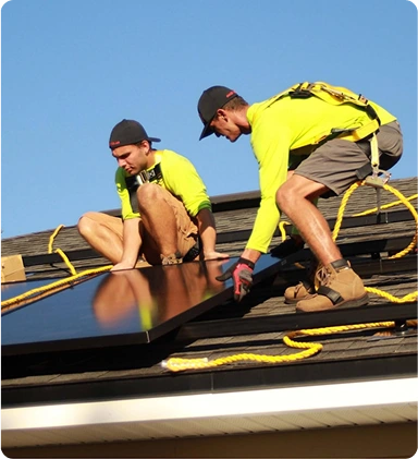 Two men installing solar panels on a roof.  