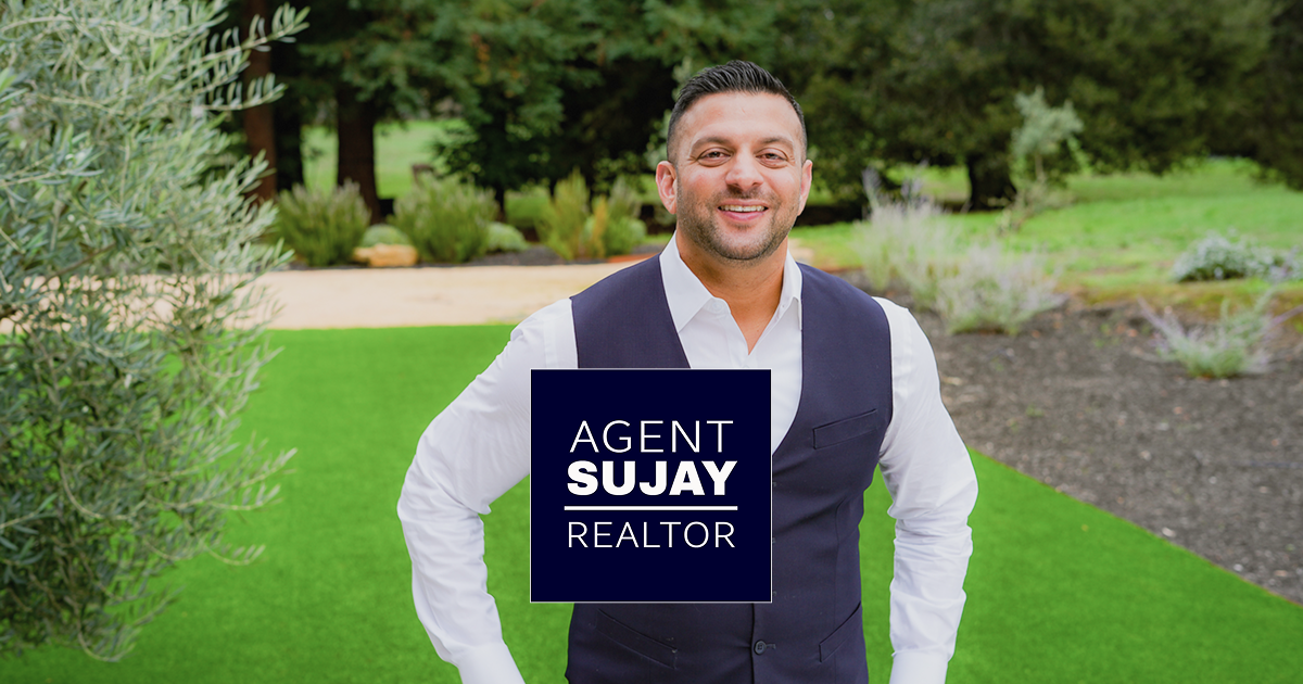 Smiling Realtor wearing a white shirt and dark vest standing outdoors on green grass with a graphic overlay that reads 'AGENT SUJAY REALTOR'.