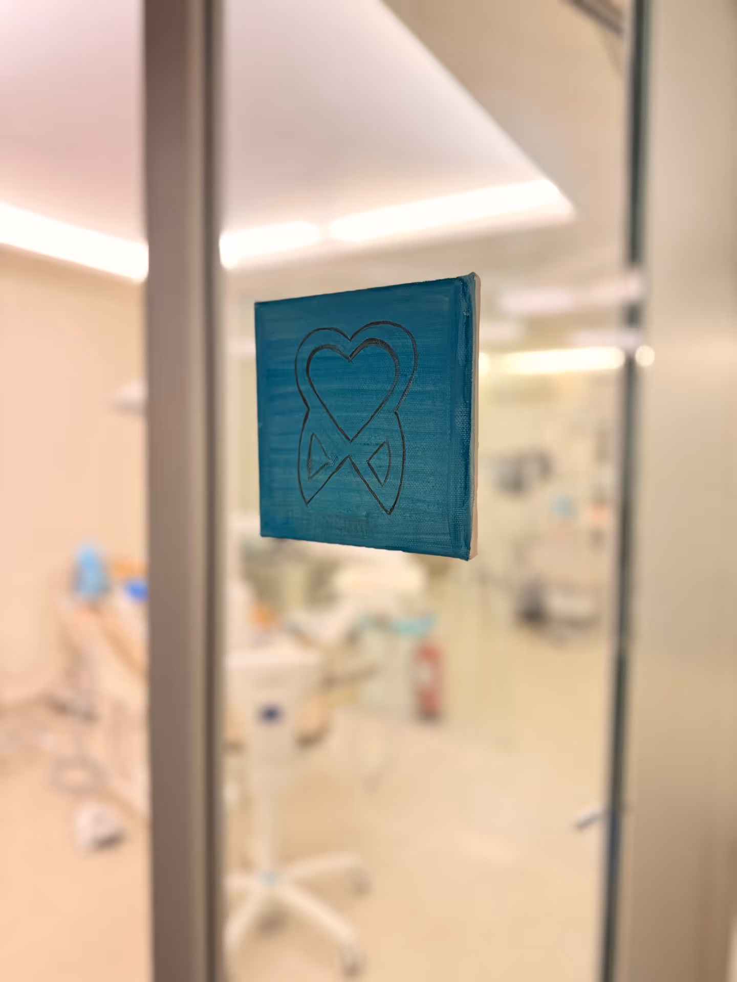 Blue square sign with a black outline of a tooth and a heart inside