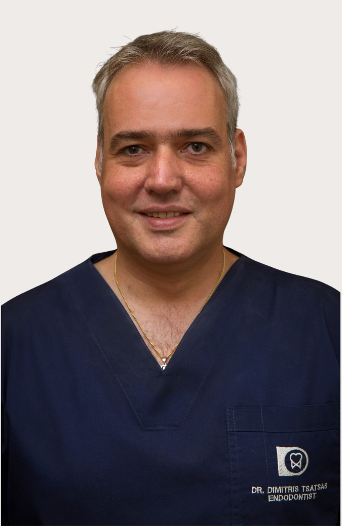 Portrait of a smiling man in navy blue medical scrubs with a gold necklace, named Dr. Dimitris Tsatsas, Endodontist.