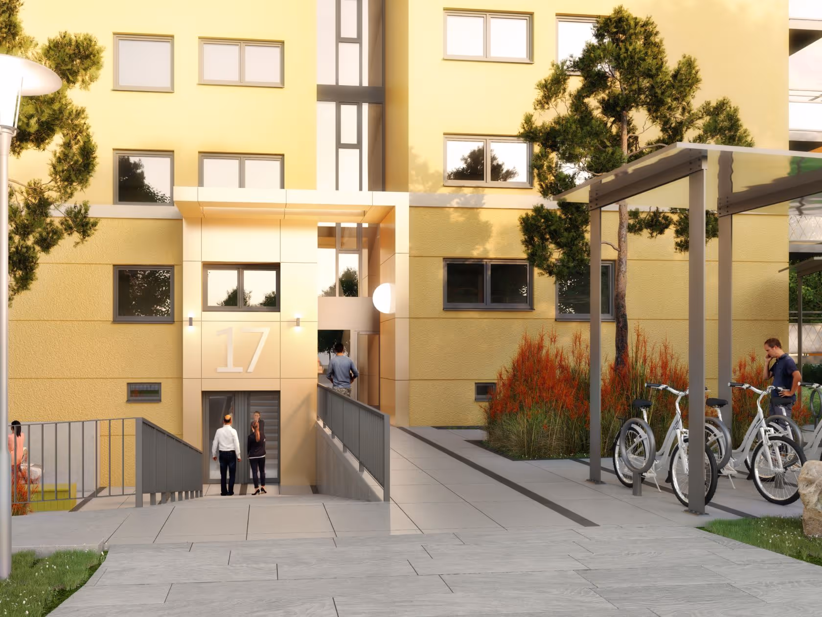 Eingang zu einem gelb gestrichenen Wohngebäude mit der Nummer 17, mehrere Personen und Fahrräder unter einem überdachten Fahrradständer.
