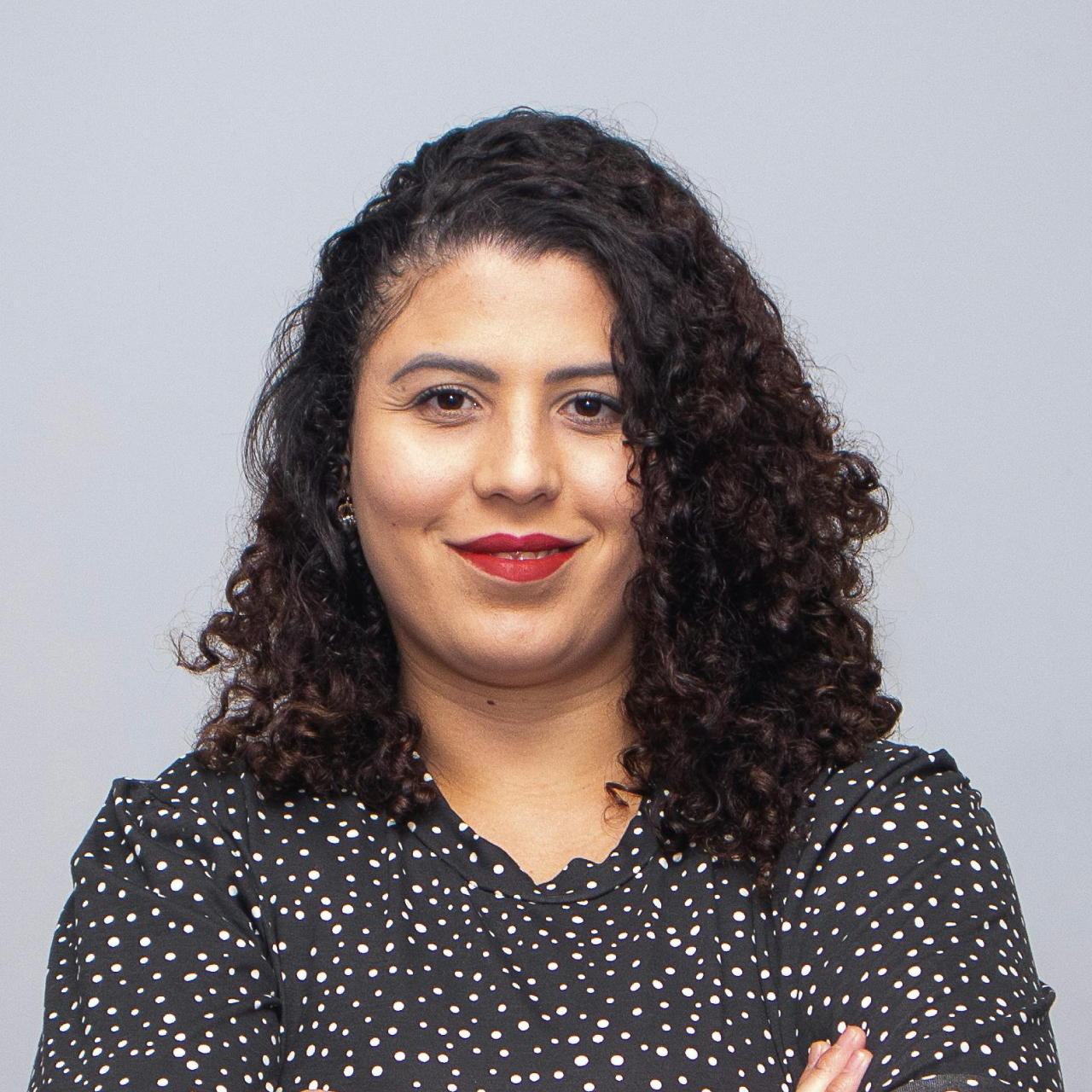 A woman with curly hair wearing a polka dot shirt.