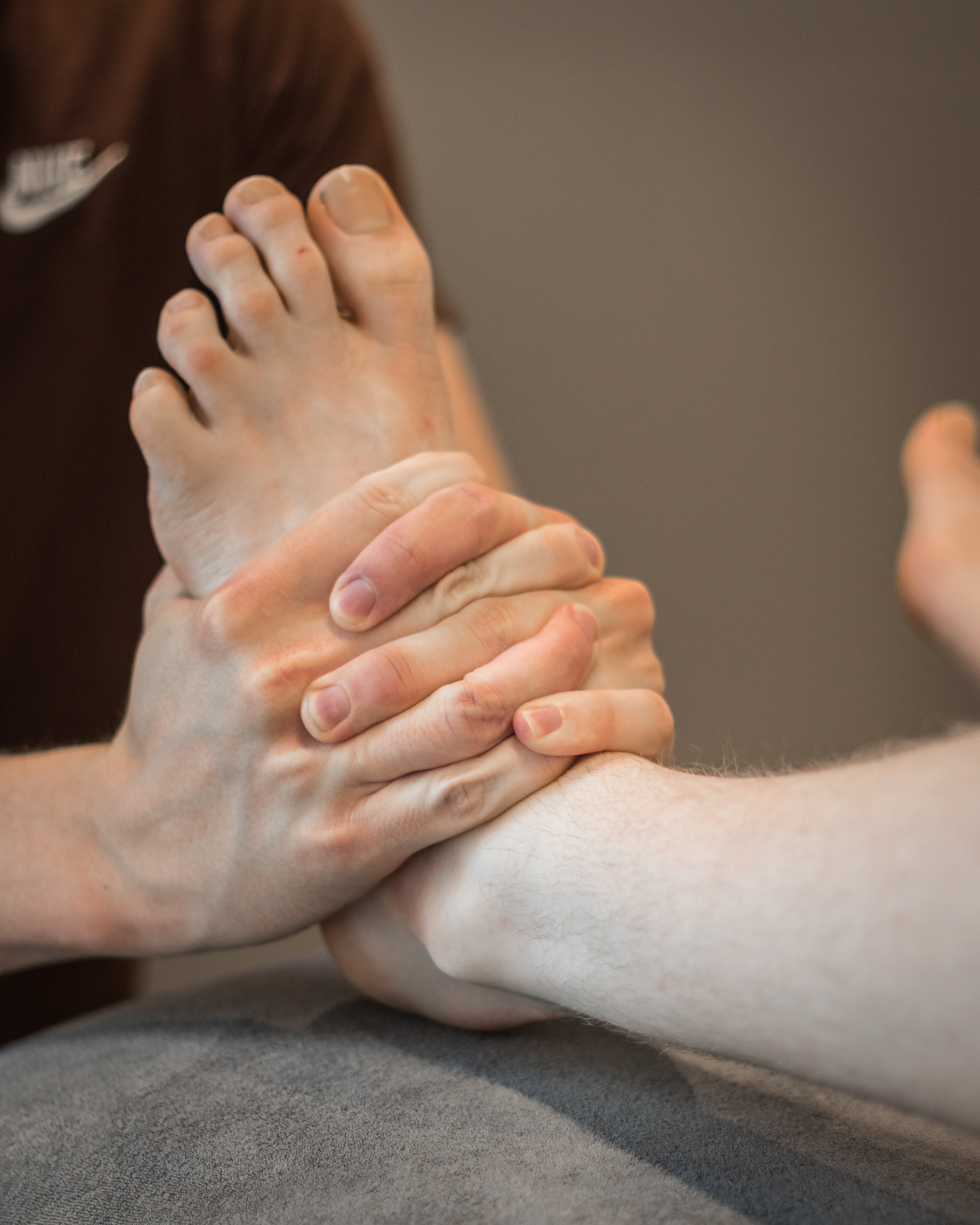 Close-up van handen die een voet vasthouden tijdens een massagesessie.