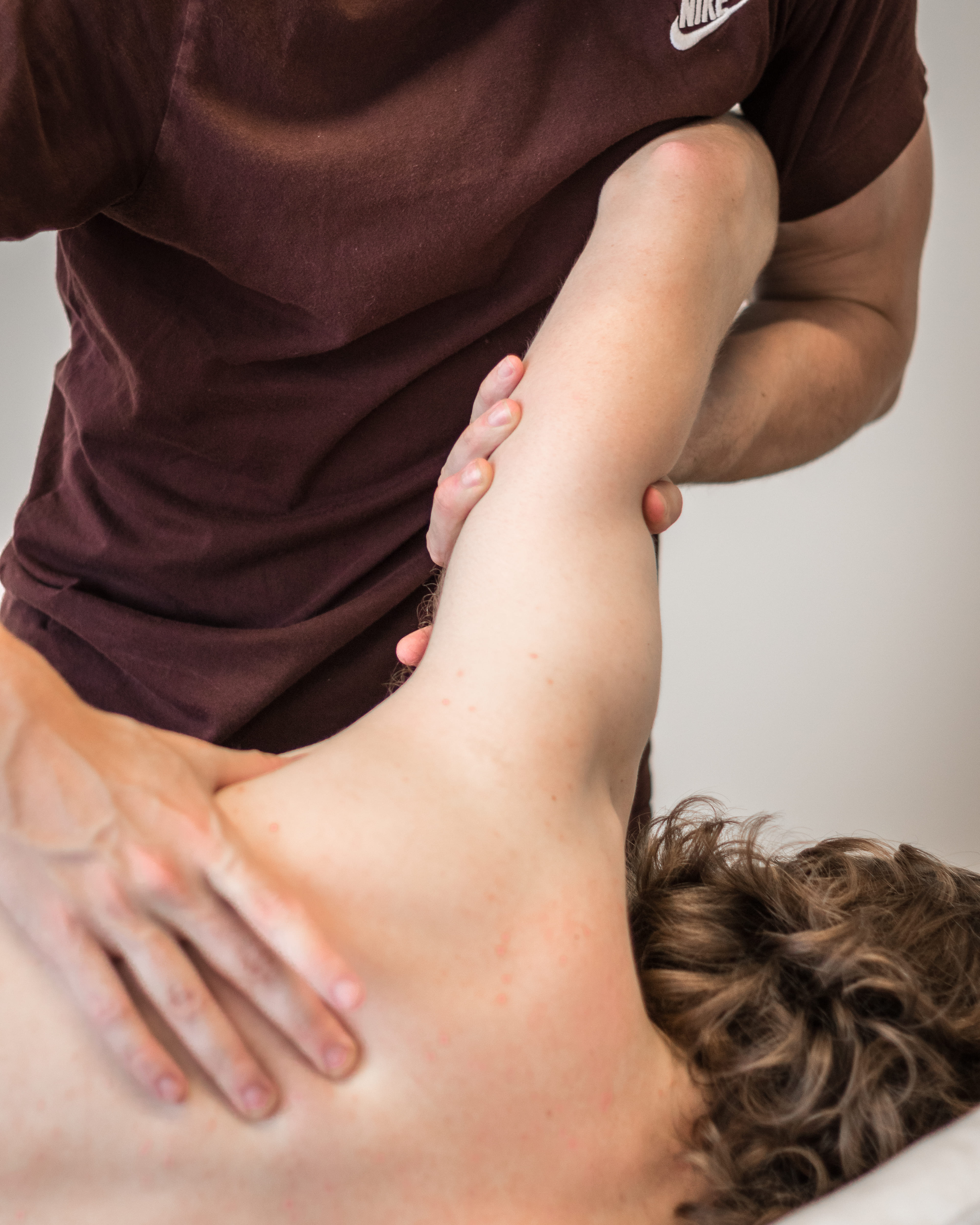 Fysiotherapeut die de bovenrug van een liggende patiënt masseert en strekt.