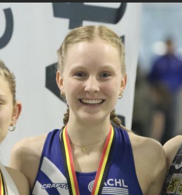 Jong meisje met gevlochten haar en een medaille rond haar nek, glimlachend in een sportieve blauwe outfit.