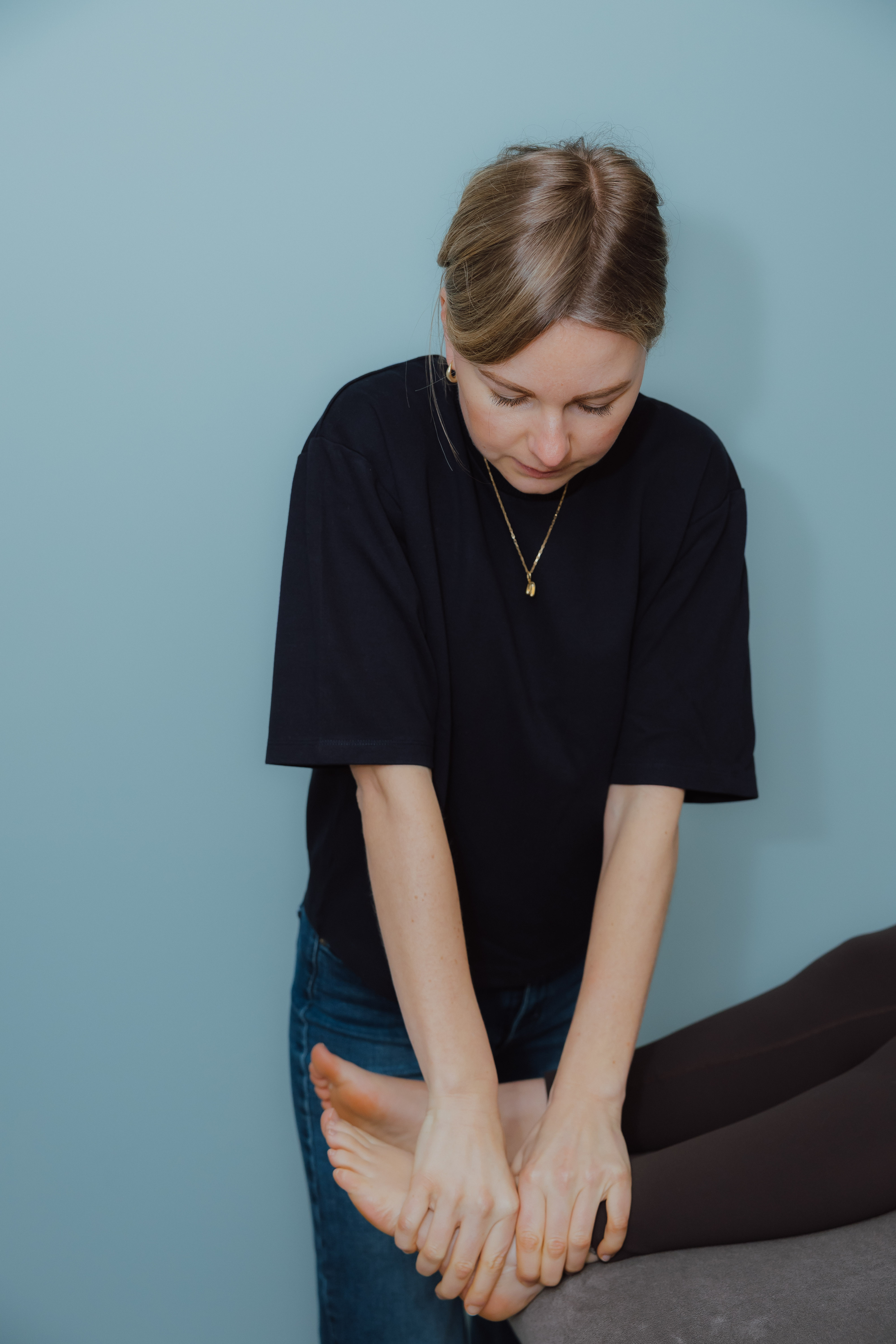 Vrouw die de voeten van een andere persoon masseert terwijl die op een tafel ligt.
