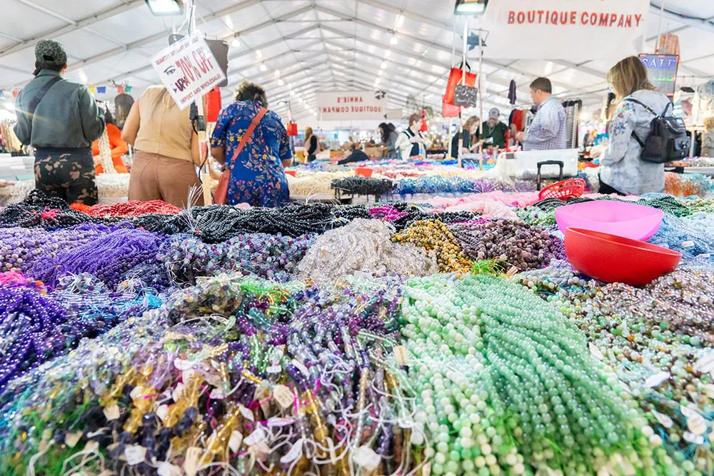 Colorful bead strands in purple, blue, green, and pink at Tucson Gem Show booth
