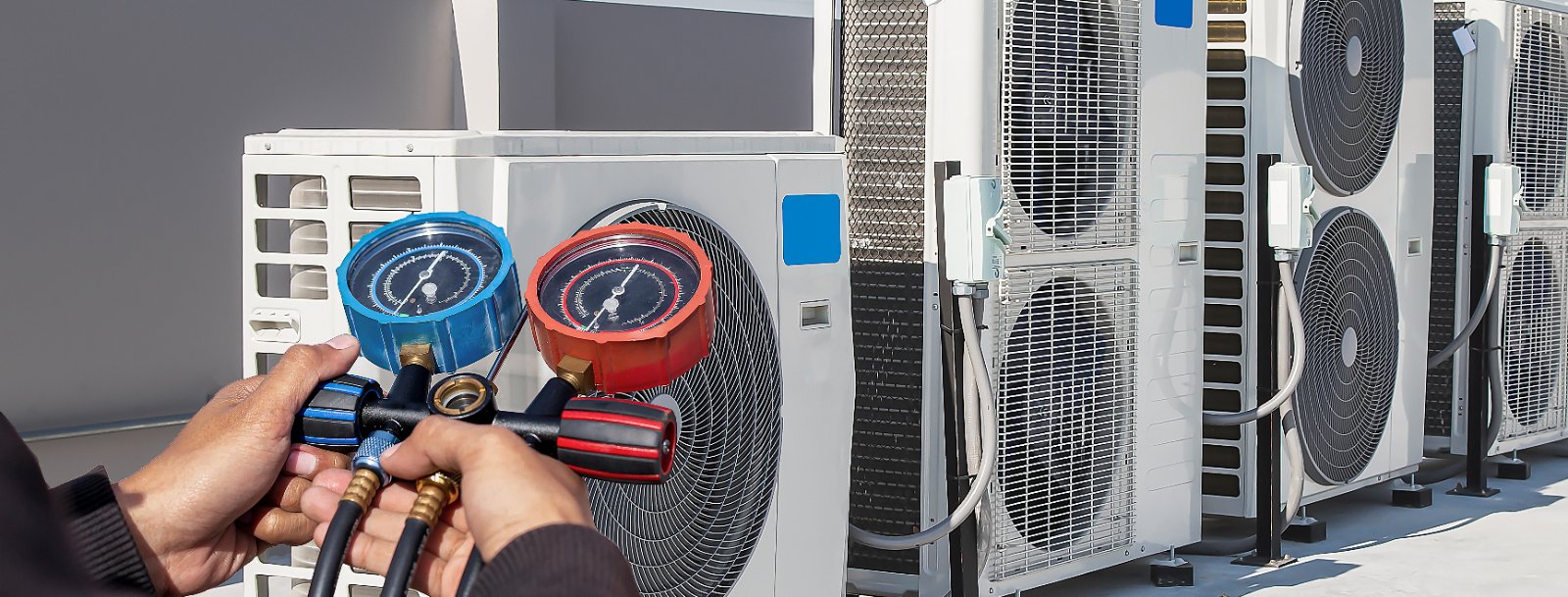 Technician reading refrigeration gauges during a preventive maintenance visit