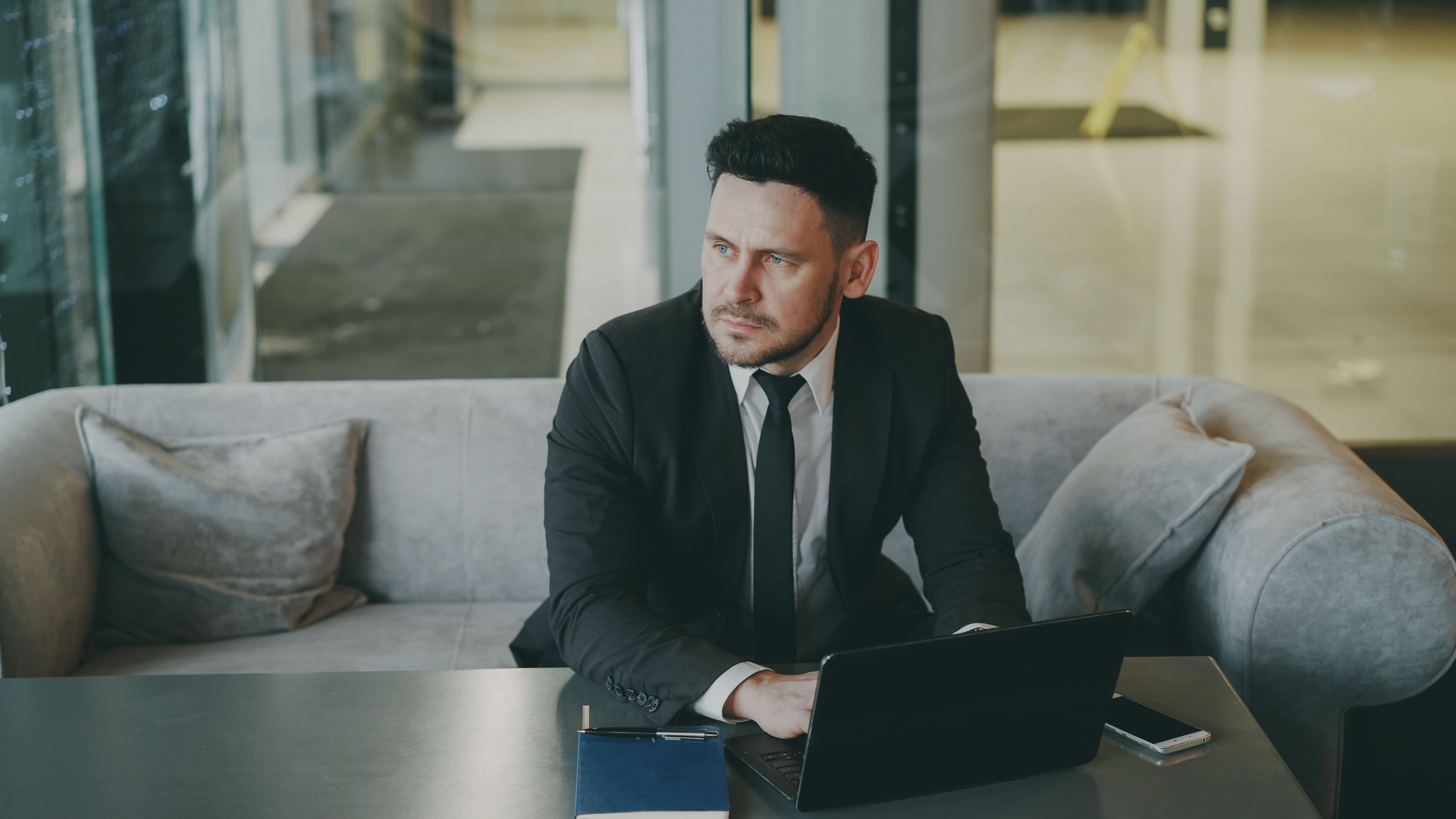 Professional executive working on a laptop in a modern office lounge.