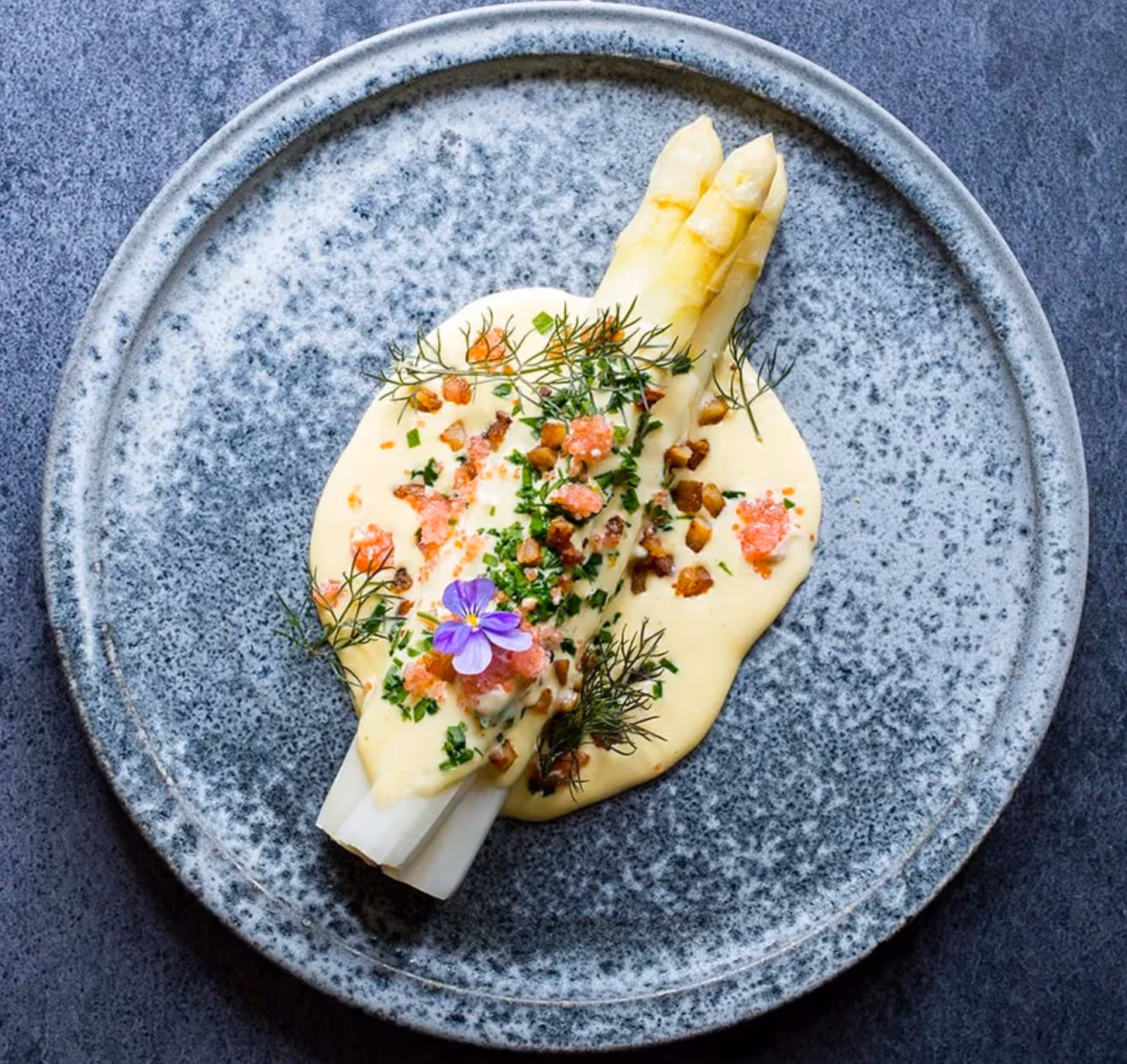 Elegant entrée with creamy sauce, herbs, and edible flowers by Exquisite Delites.