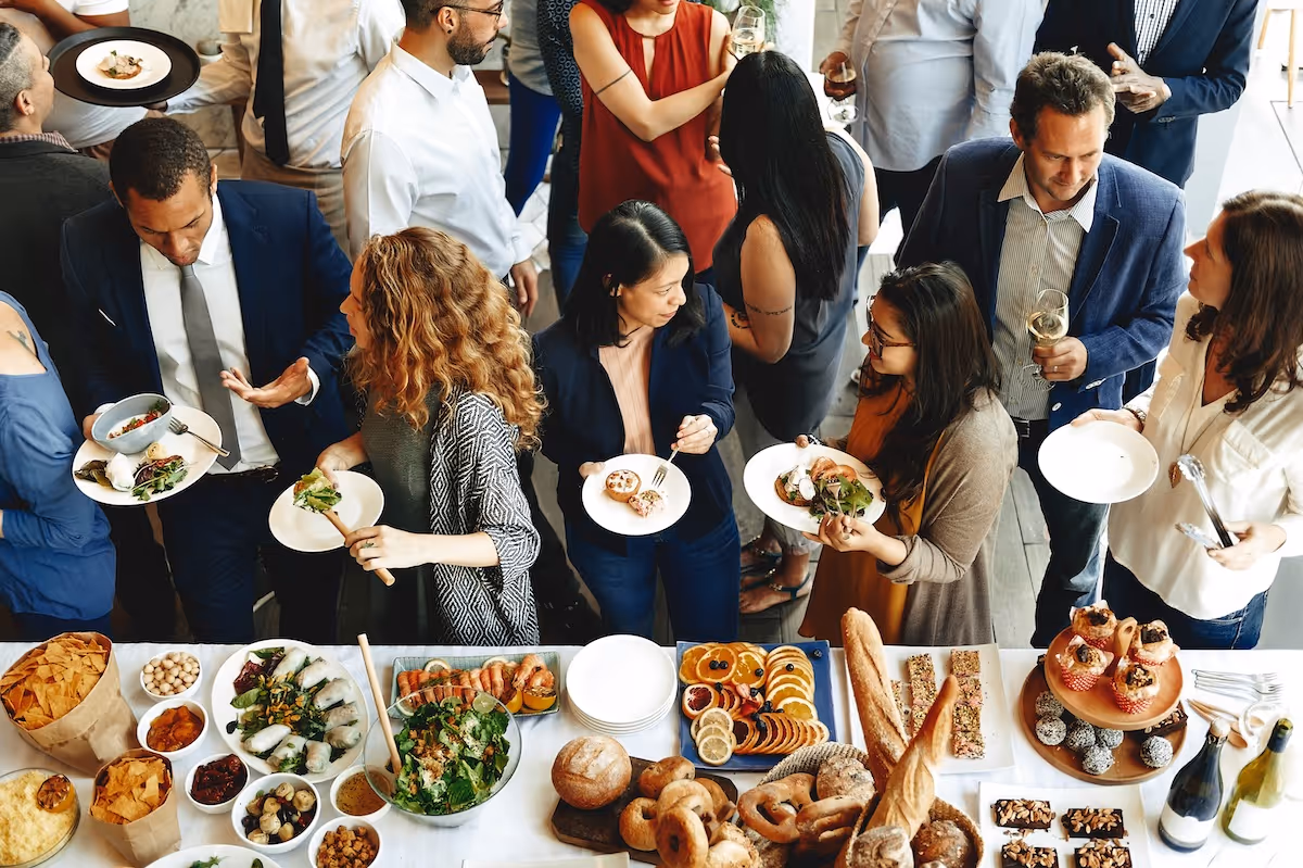 Corporate guests at a buffet of bread, salads, and gourmet dishes by Exquisite Delites.
