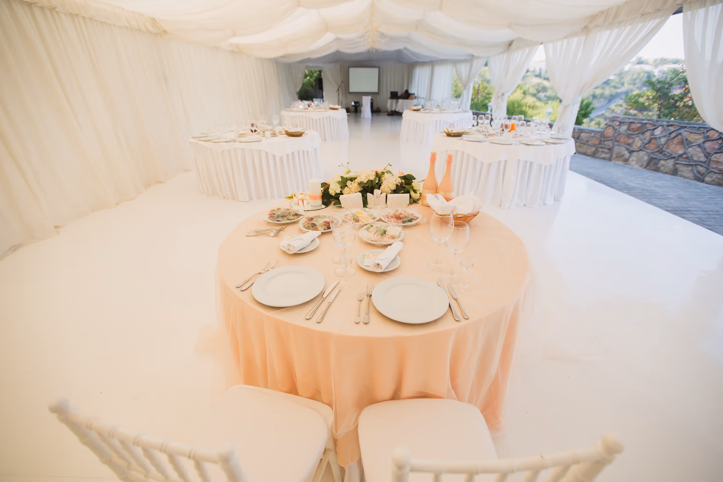 Elegant venue with round tables, peach linens, and florals by Exquisite Delites, Atlanta.