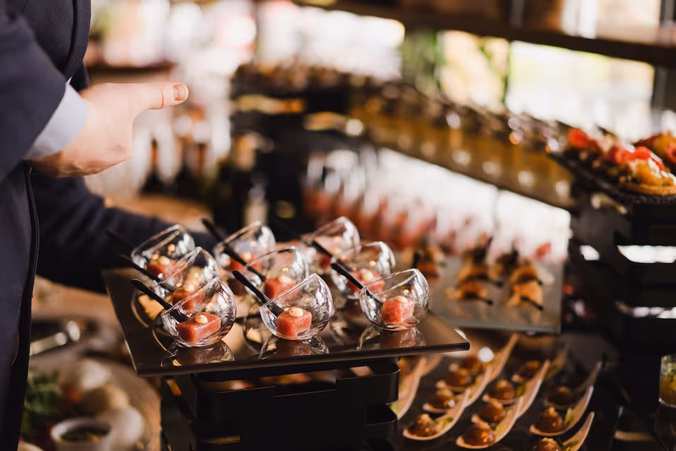 Server presenting appetizers in glass bowls for cast and crew by Exquisite Delites, Atlanta.