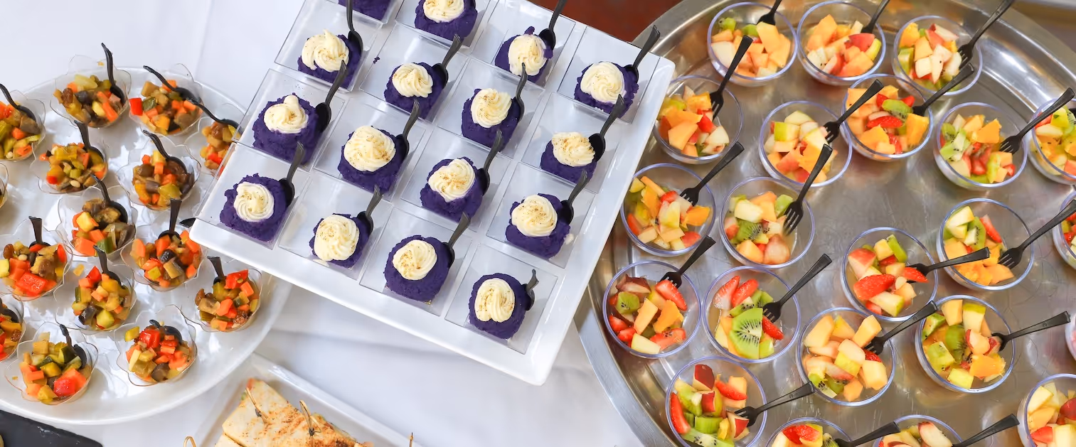 Assorted fruit cups and purple mousse desserts by Exquisite Delites for film set catering.
