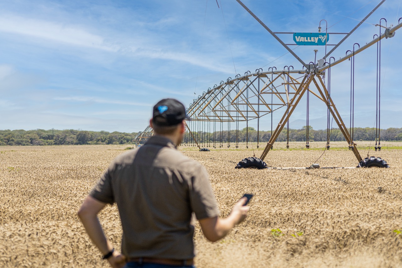 Man standing in field with center pivot
