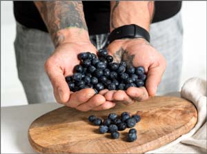 A person holding a handful of blueberries