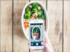 A person taking a photo with their phone of a prepared meal