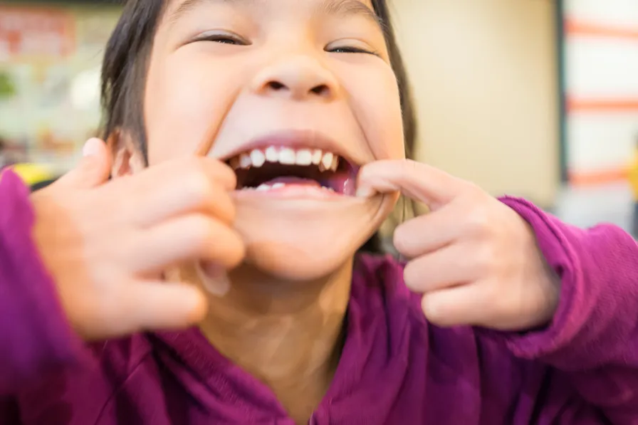 child opening her mouth showing crooked teeth