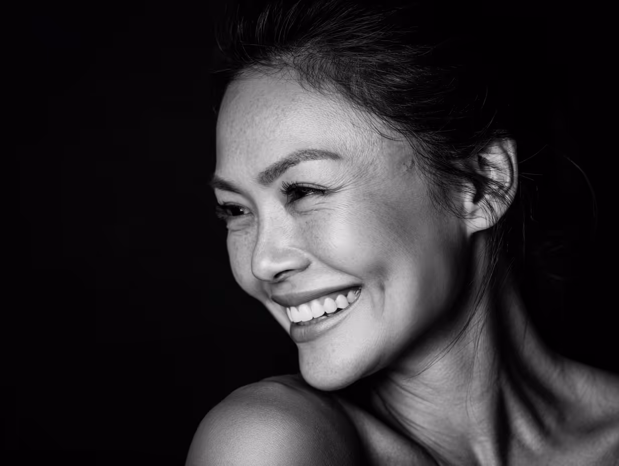 Black and white close-up of a woman smiling and looking to her left.